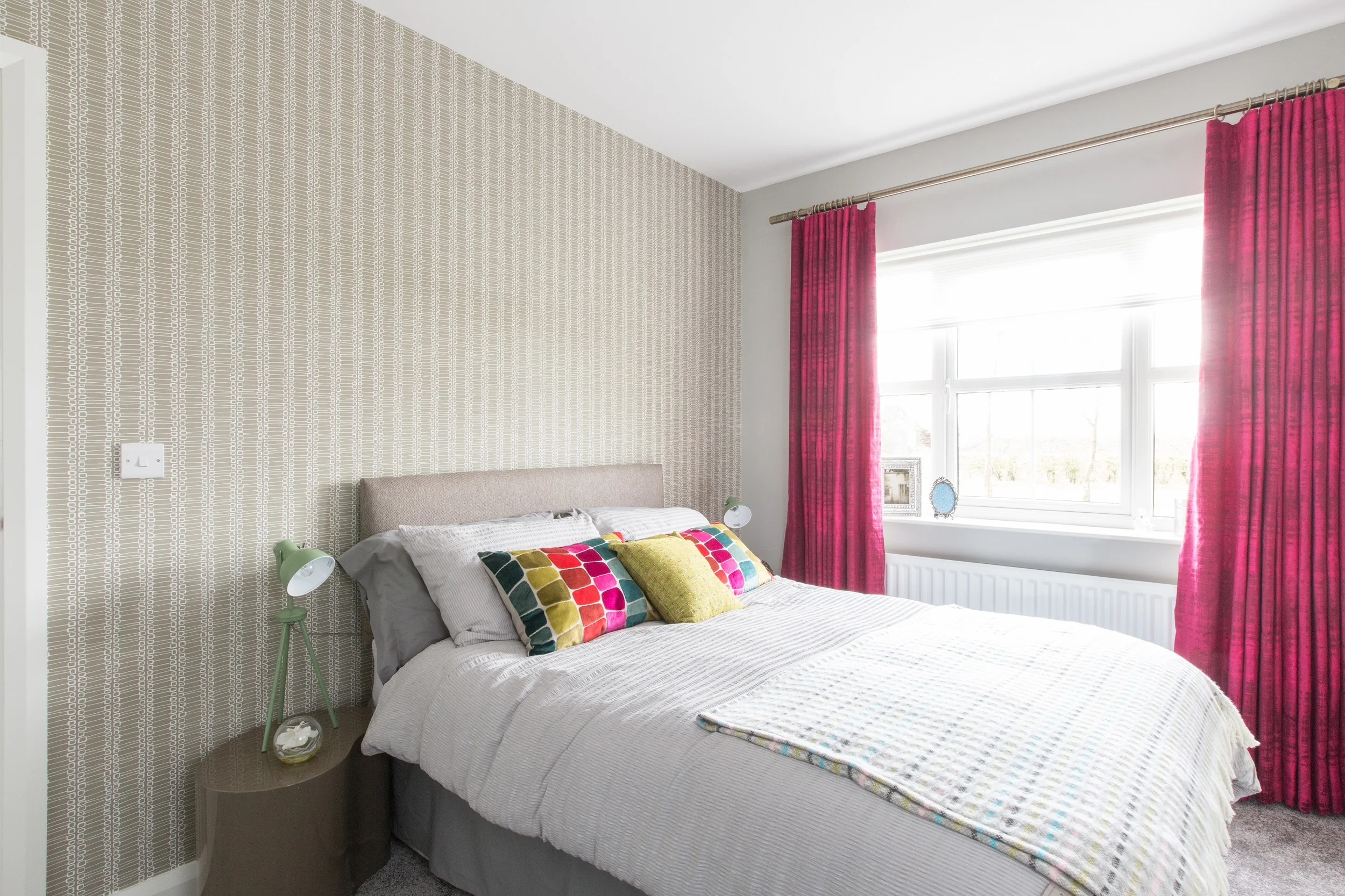 A sumptuous set of daring fuchsia drapes enrich this bedroom. Bright velvet scatter cushions in an otherwise completely neutral room make this scheme eye catching without being overpowering.