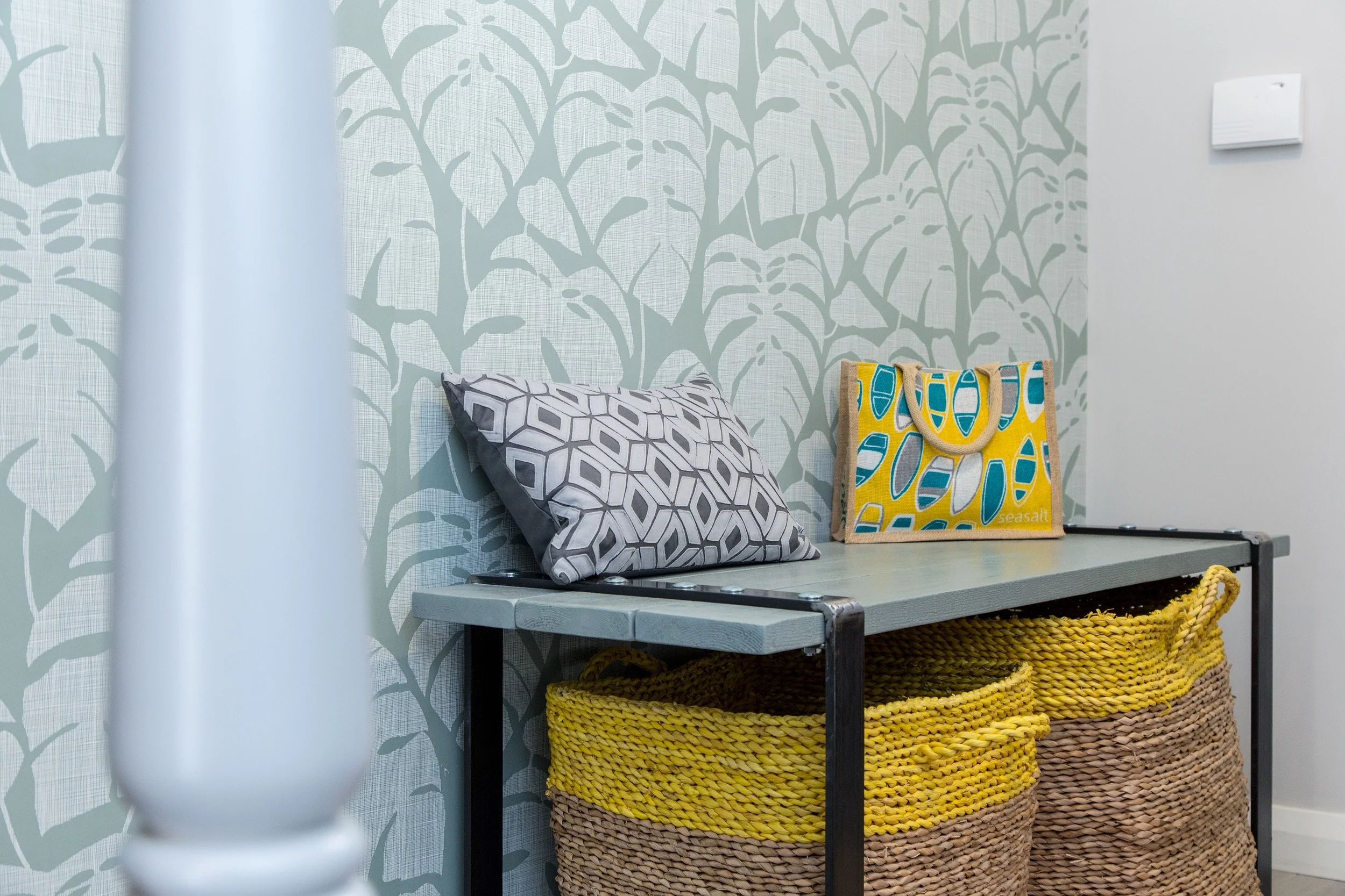 Pale grey tones for woodwork on the stairs and bespoke bench soften these hard features, drawing out the stronger tones of the metal and bright yellow detailing.