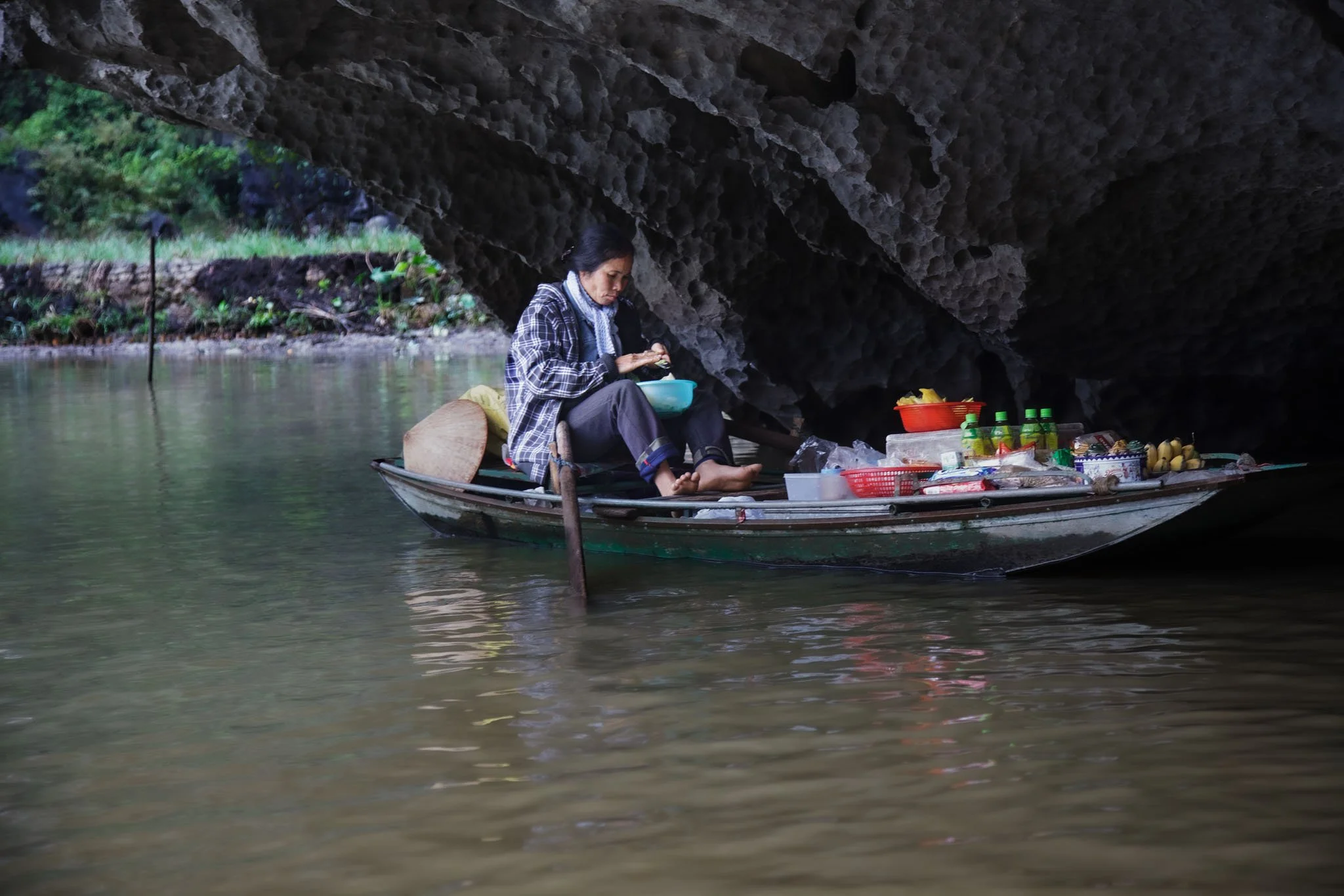 Marchande flottante cuisinant sous la grotte