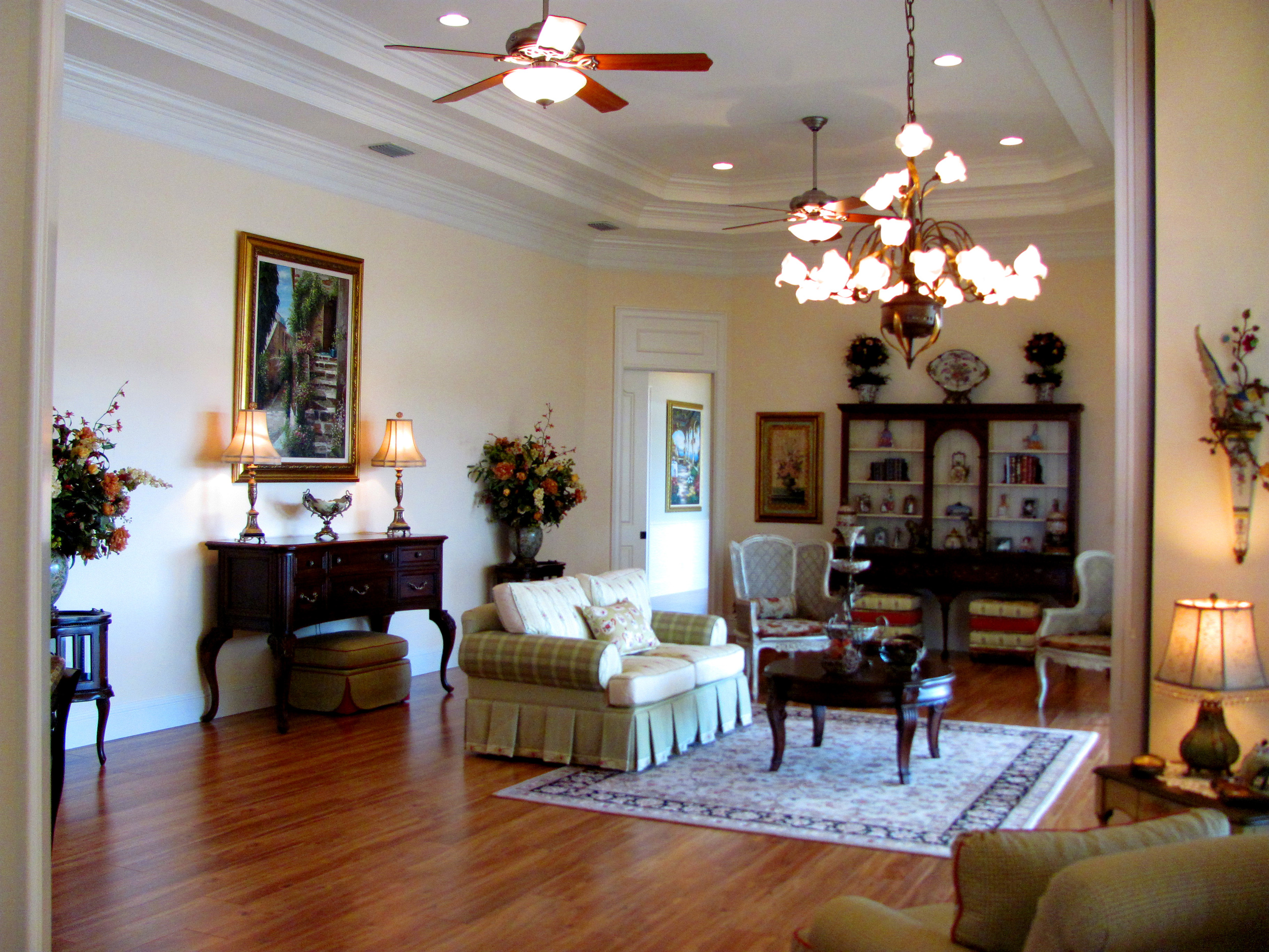 Formal living room features triple tray ceilings, crown moldings and custom wood floors