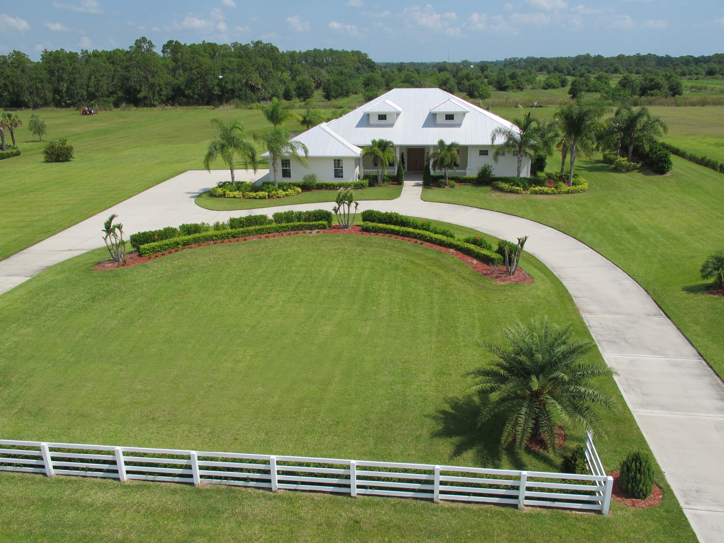 Aerial image of the front of a large ranch estate with a long circular driveway