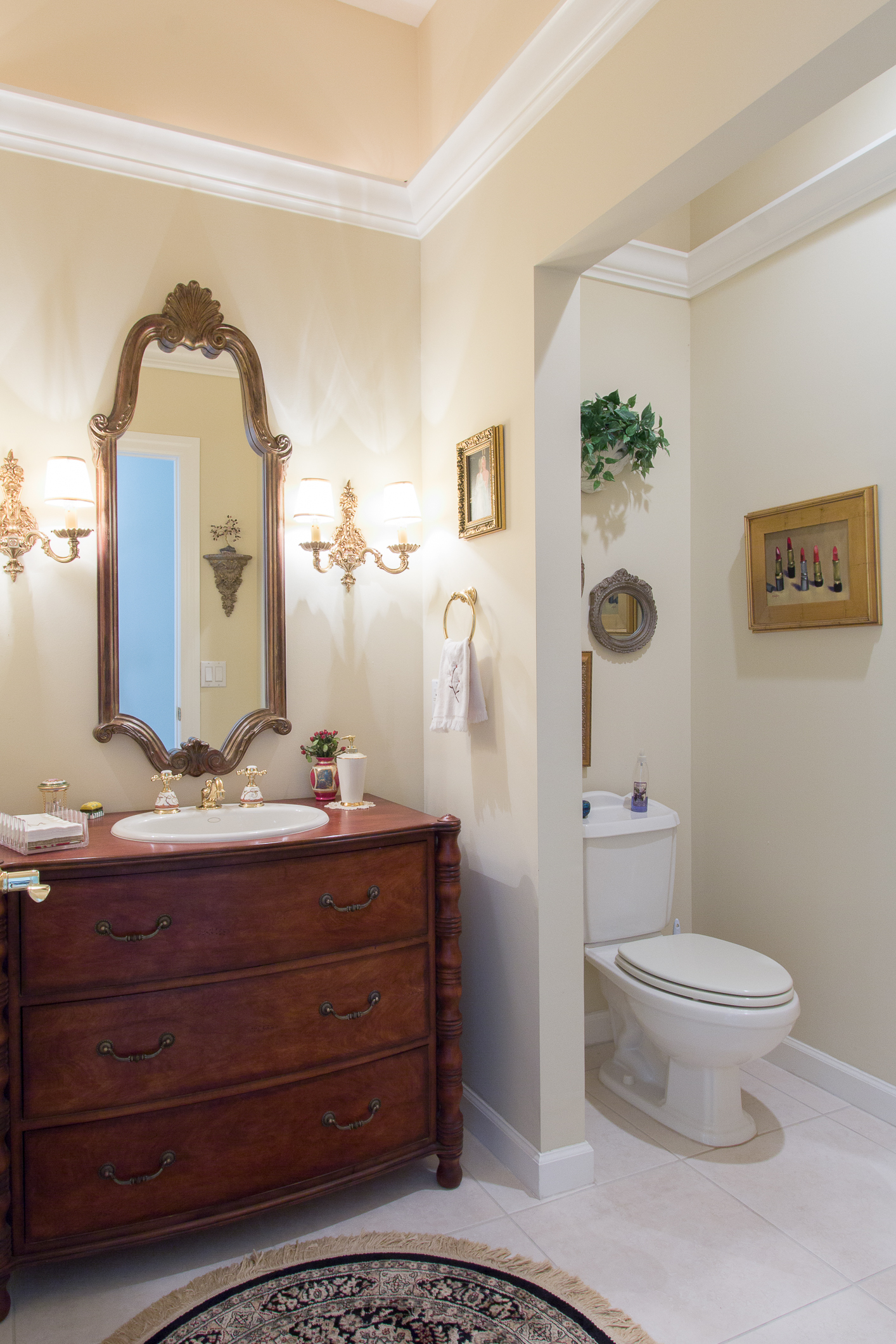 A vertical photograph of a bathroom with dresser vanity and crown molding