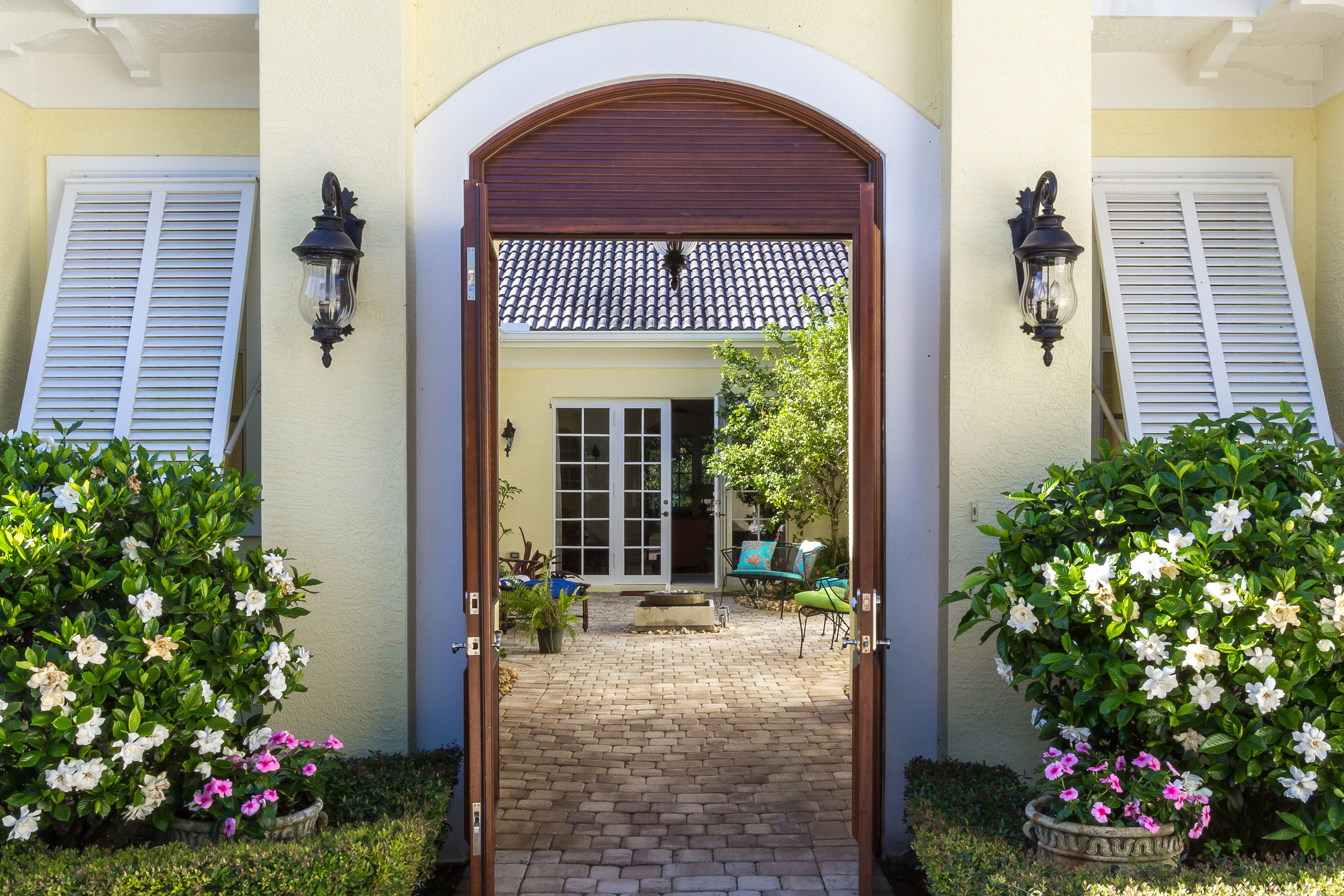 Courtyard entrance at the Estuary with arched doorway flanked by beautiful gardenias