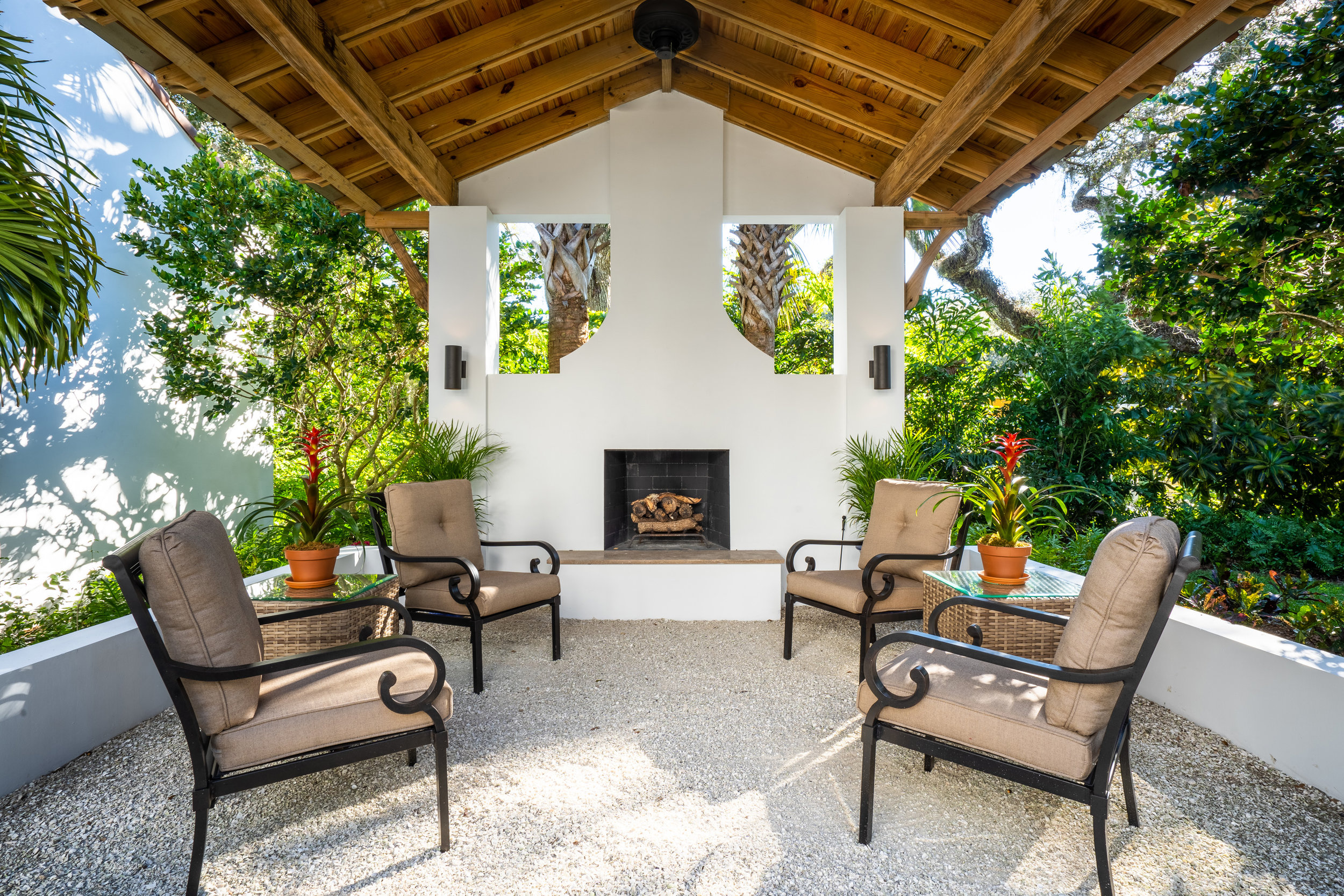 Covered outdoor gathering space has entertaining and dining space in front of a fireplace