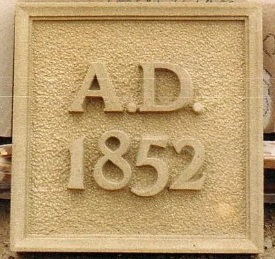 Buff sandstone date stone with raised letters and sparrow pecked background