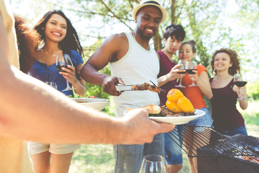 Group of friends making barbecue in the nature. Eating and shari