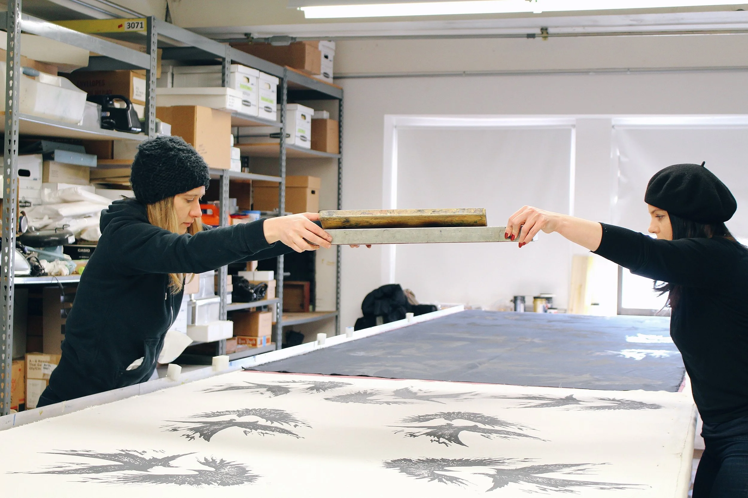 Girl positions press above textile to create raven design showing off the process of creating women's clothing