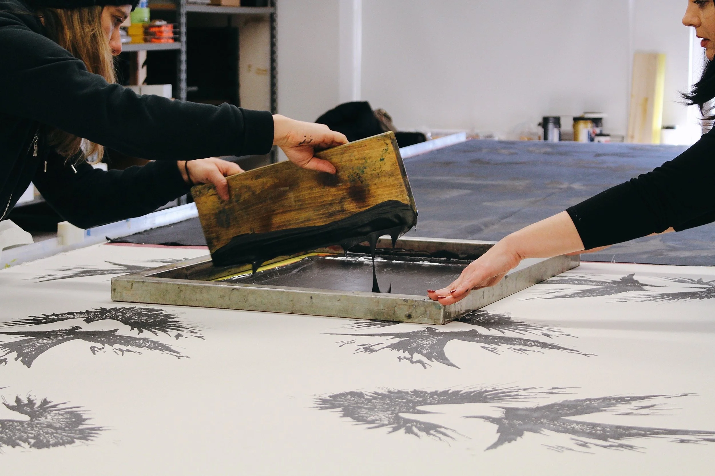 Two workers fill stamp with black ink substance at Veil and Valor studio