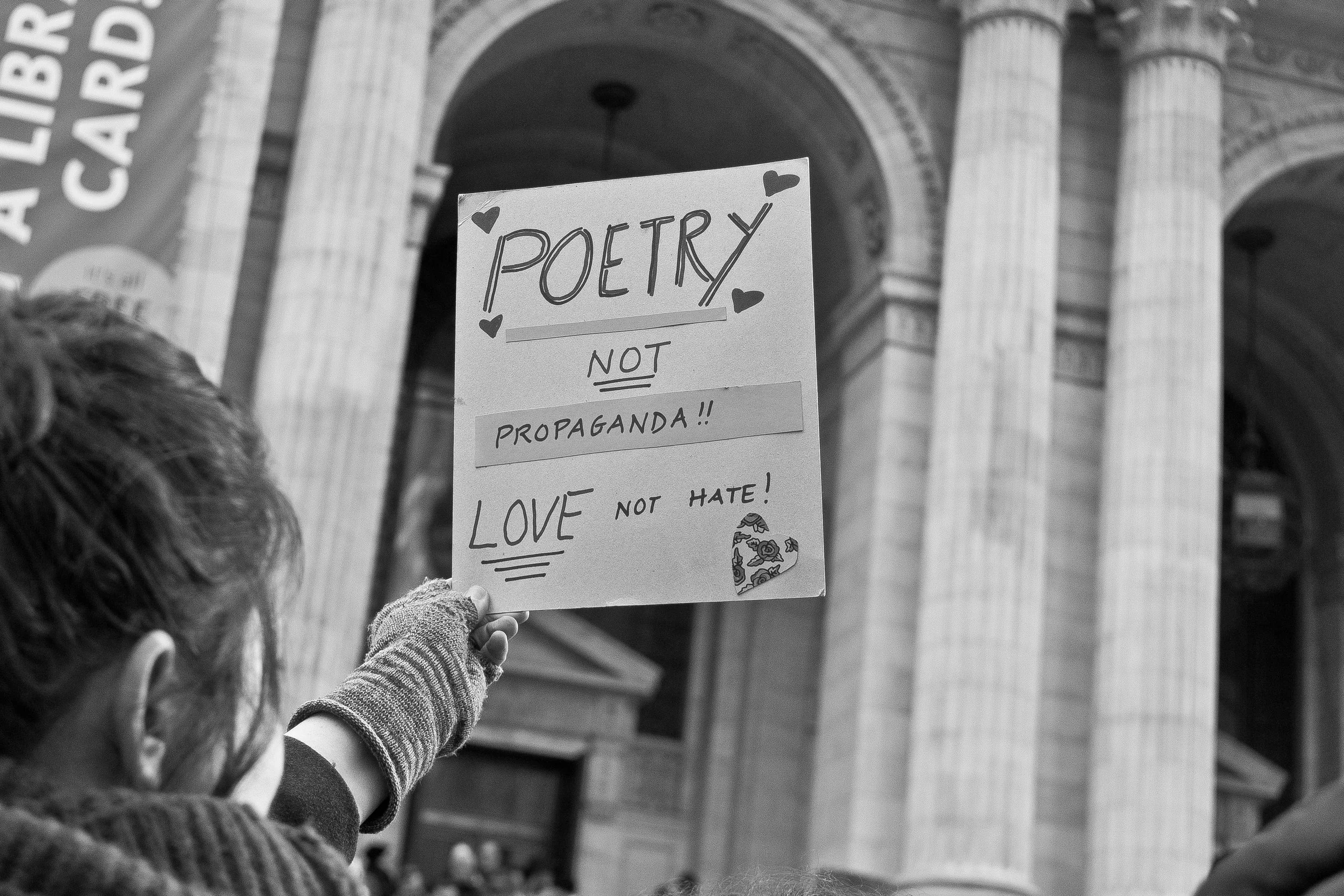 A poet holds up a sign outside of the New York Public Library during the Writers Resist action. 