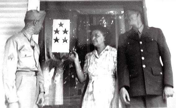 Victoria Tessier touched the five-star flag displayed at the family’s West End home during World War II with sons Albert (left) and Louis. While the two men survived the war, they died soon after. Louis, the oldest of the six brothers, had a fatal heart condition. Albert had contracted malaria in the Pacific theater and never recovered. Photo courtesy Hope Tessier.