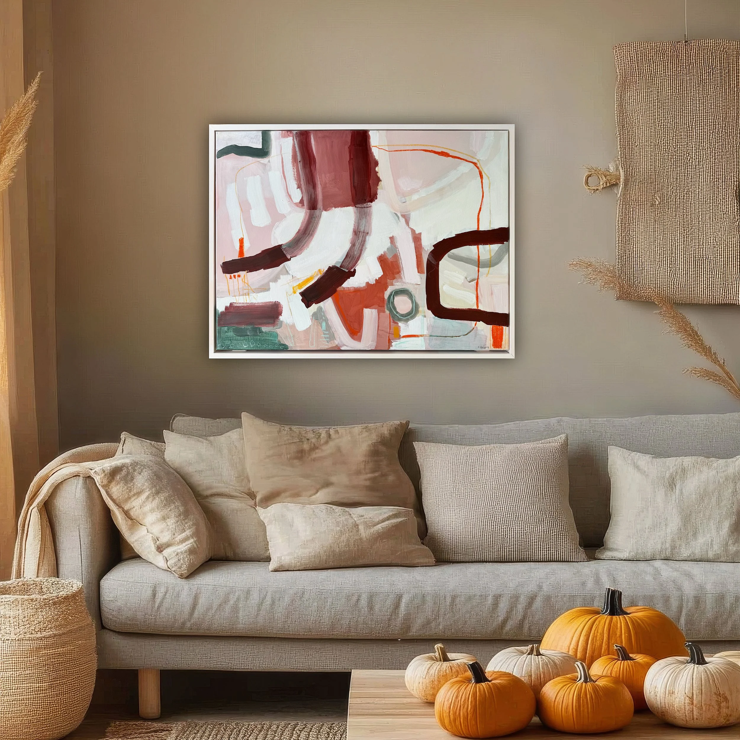 light pink framed abstract painting with brown lines and forms hanging on a cozy fall living room wall