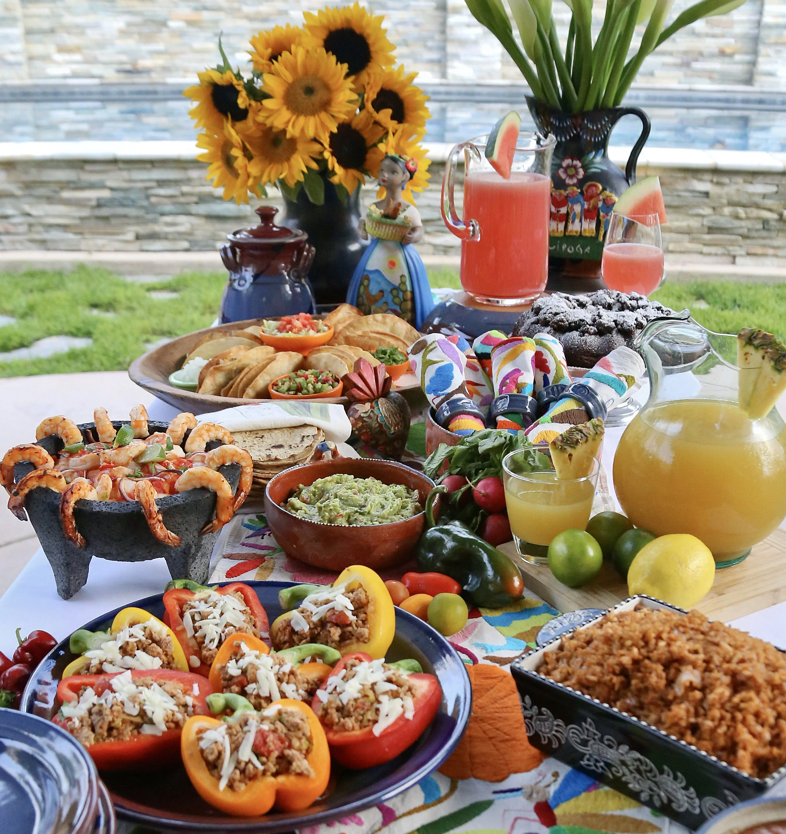 Table filled with bright colors, flowers and Mexican Food