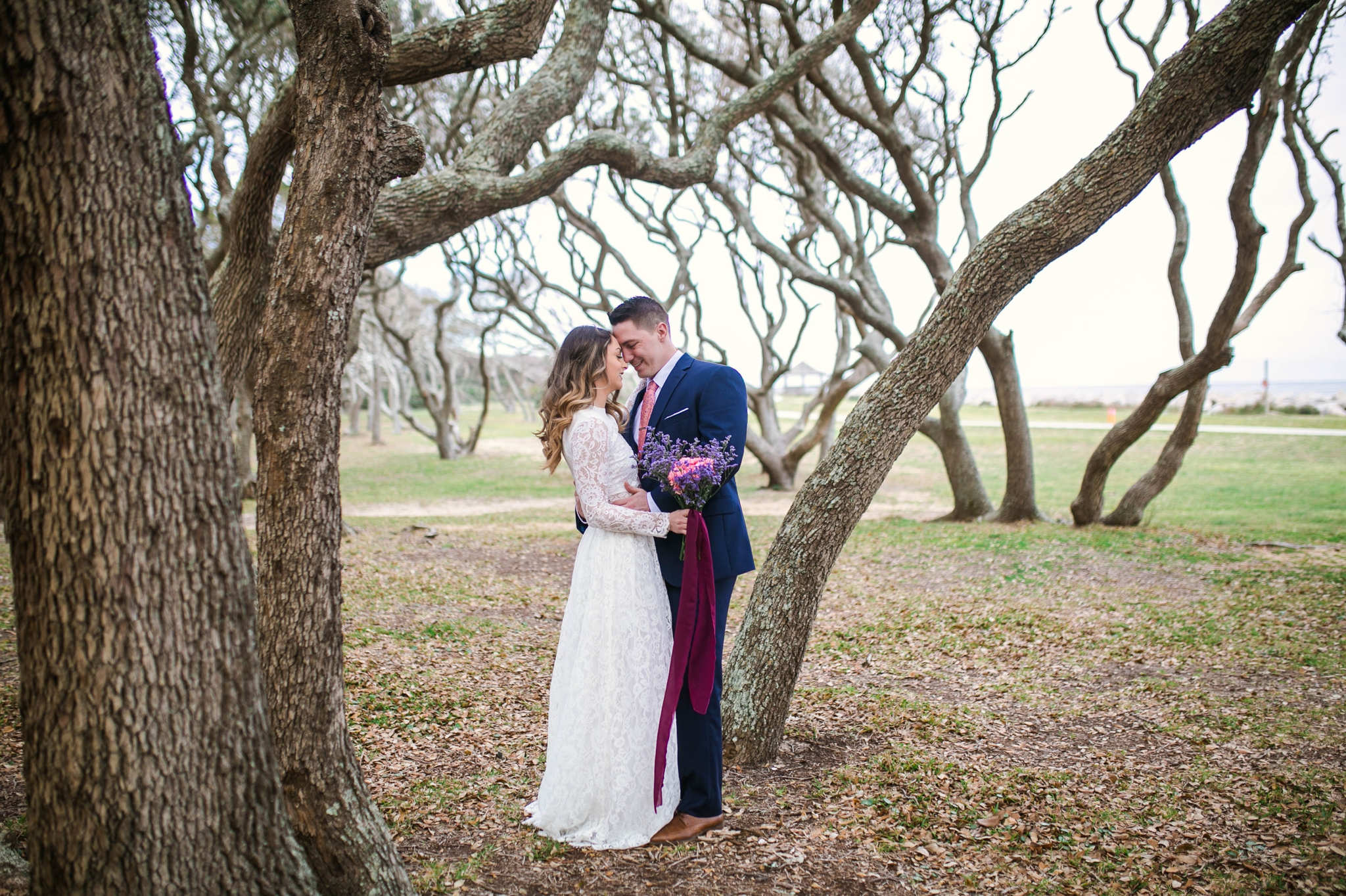 Beach Elopement Photography within the oak trees - dress by asos with purple and pink flowers and navy suit - oahu hawaii wedding photographer 