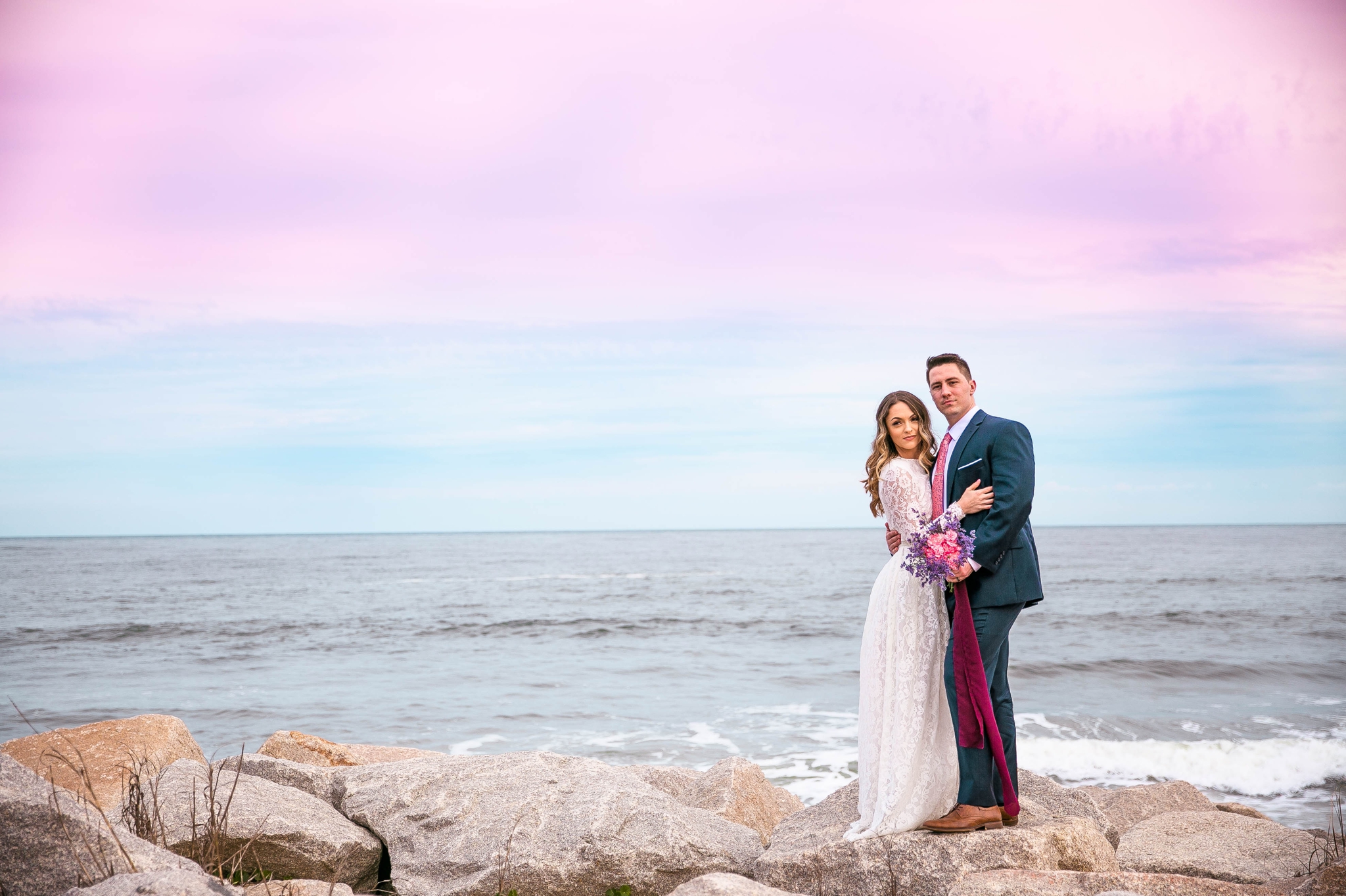 beach Elopement portraits on top of the cliffs - - dress by asos with purple and pink flowers and navy suit - oahu hawaii wedding photographer