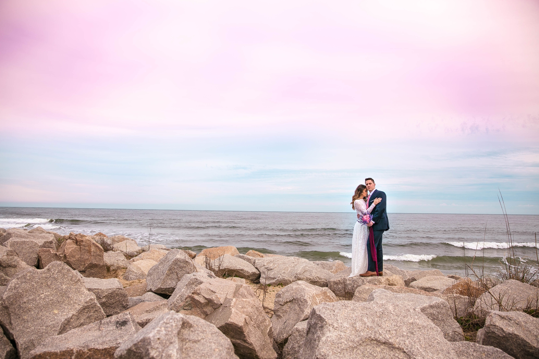 Cotton Candy Sky Beach Elopement Portraits - Bride and Groom on top of the Cliffs - - dress by asos with purple and pink flowers and navy suit - oahu hawaii wedding photographer