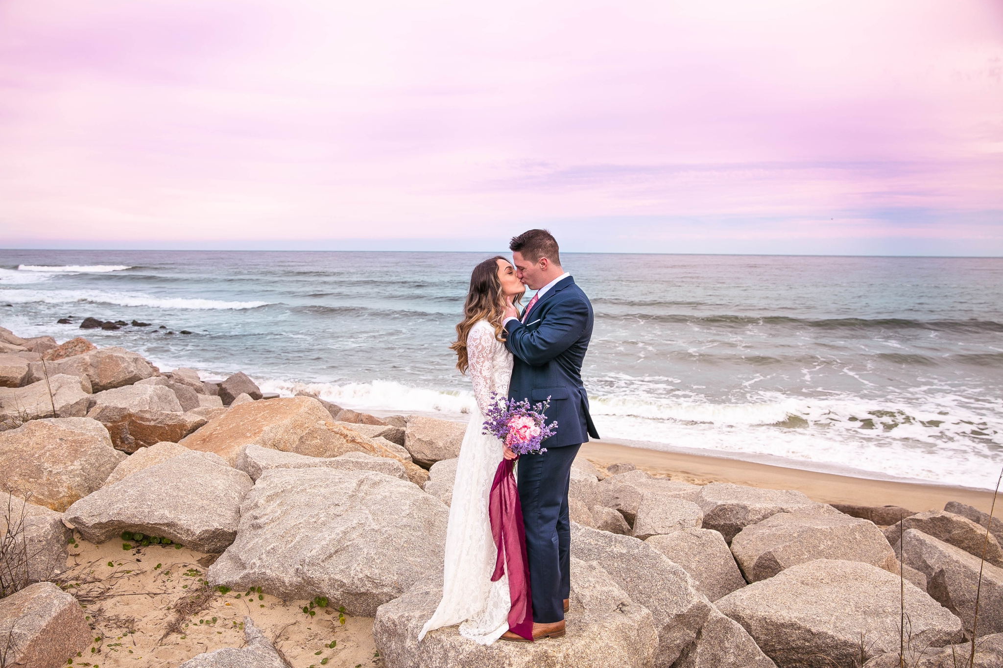 Cotton Candy Sky Beach Elopement Portraits - Bride and Groom on top of the Cliffs - - dress by asos with purple and pink flowers and navy suit - oahu hawaii wedding photographer