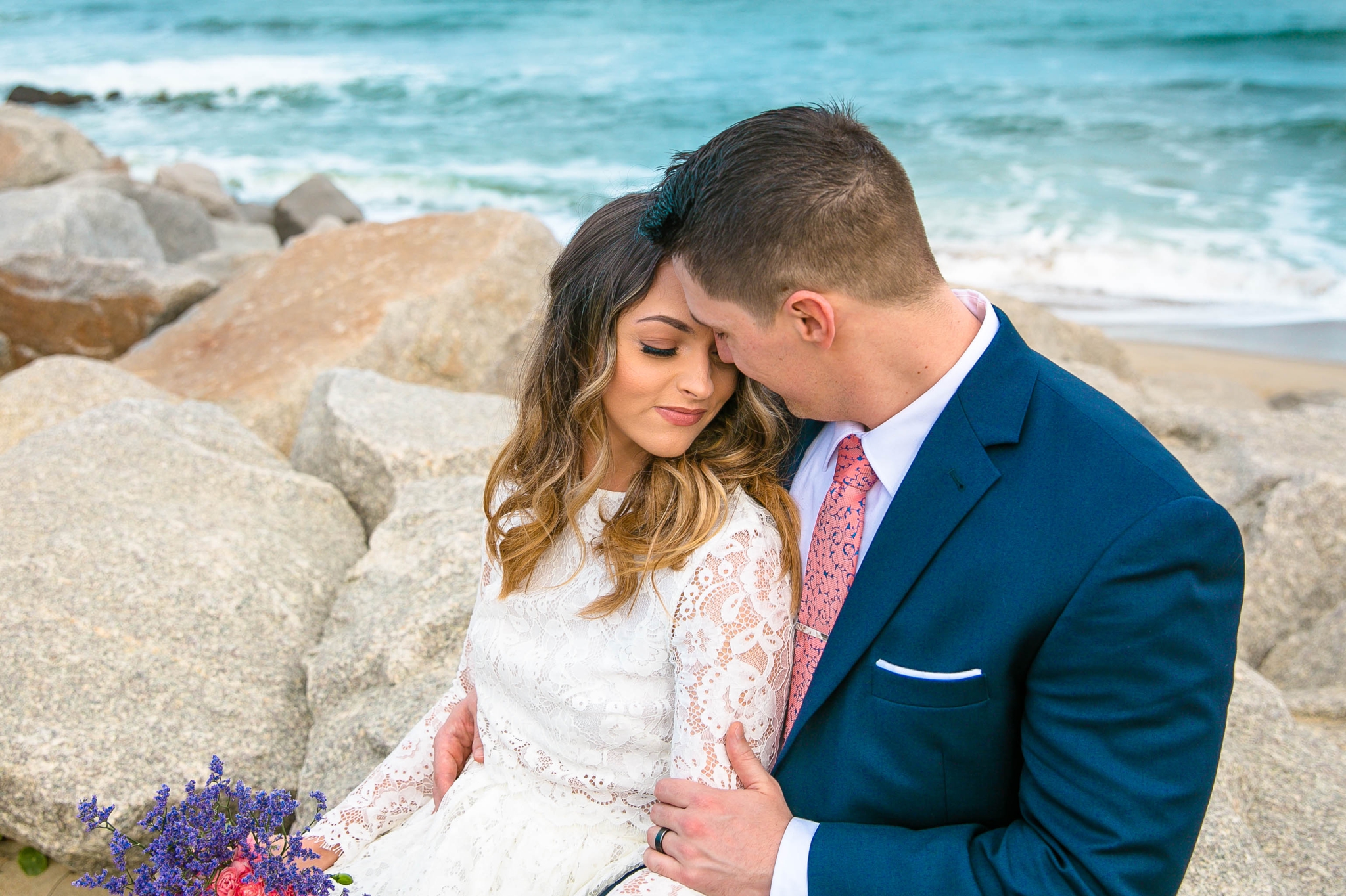 Clear blue water Beach Elopement Portraits - Bride and Groom on top of the Cliffs - - dress by asos with purple and pink flowers and navy suit - oahu hawaii wedding photographer