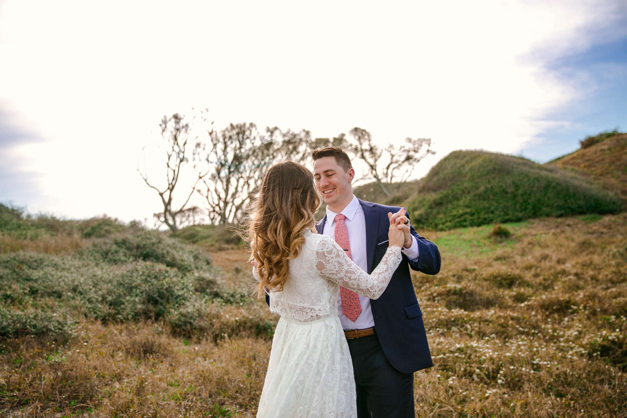 Bride and groom dancing in Lush Green Grass - Beach Elopement Photography - wedding dress by asos with purple and pink flowers and navy suit - oahu hawaii wedding photographer