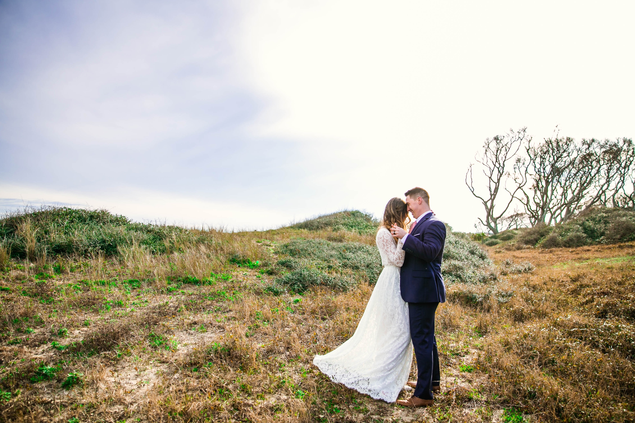 Bride and Groom in Lush Green Hills - Beach Elopement Photography - wedding dress by asos with purple and pink flowers and navy suit - oahu hawaii wedding photographer