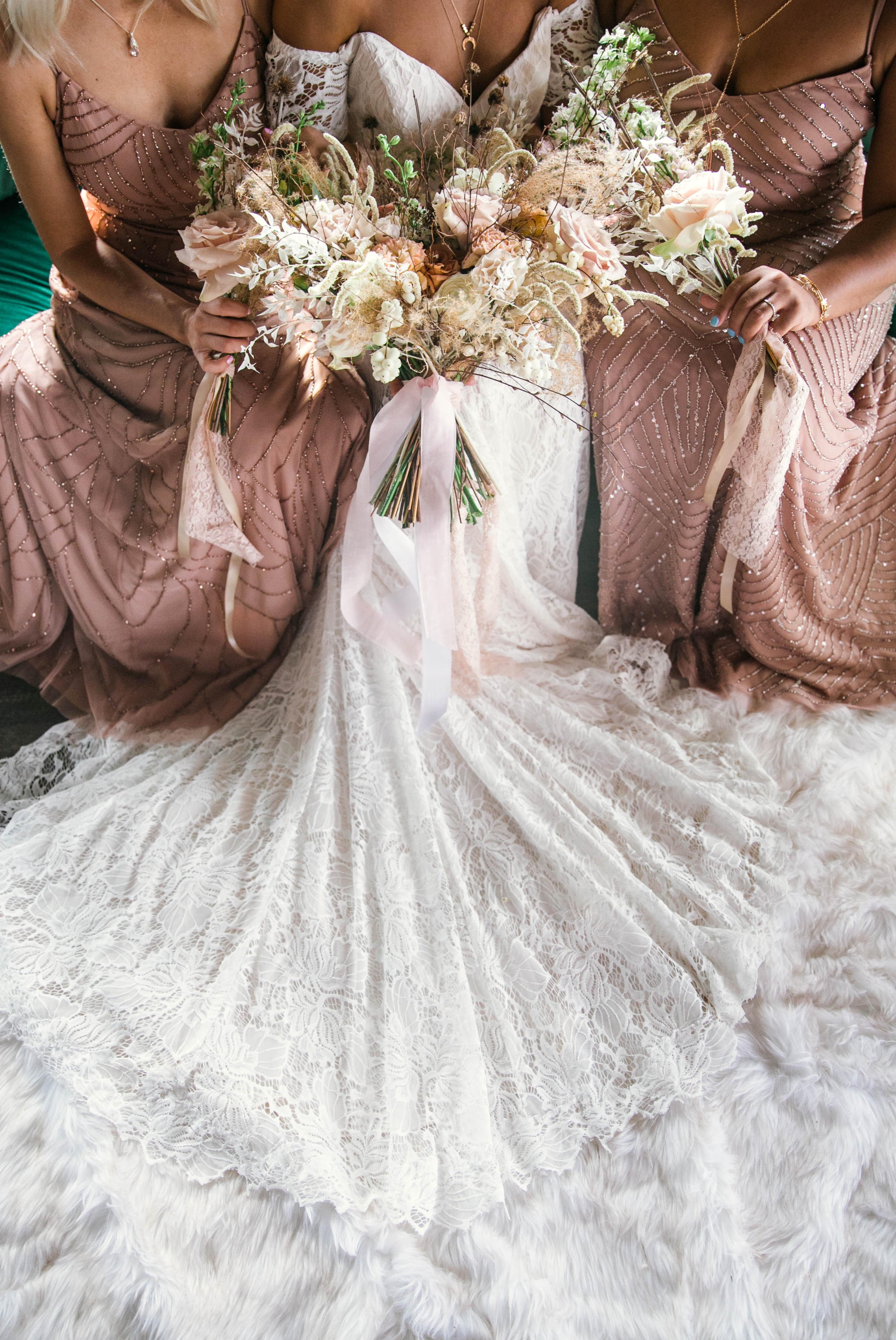  Indoor Natural light portrait of a black bride and her bridesmaids in a boho wedding dress with light pink bridesmaids dresses sitting on an emerald tufted sofa - laughing and having fun with each other- flowers in natural african american hair - oa