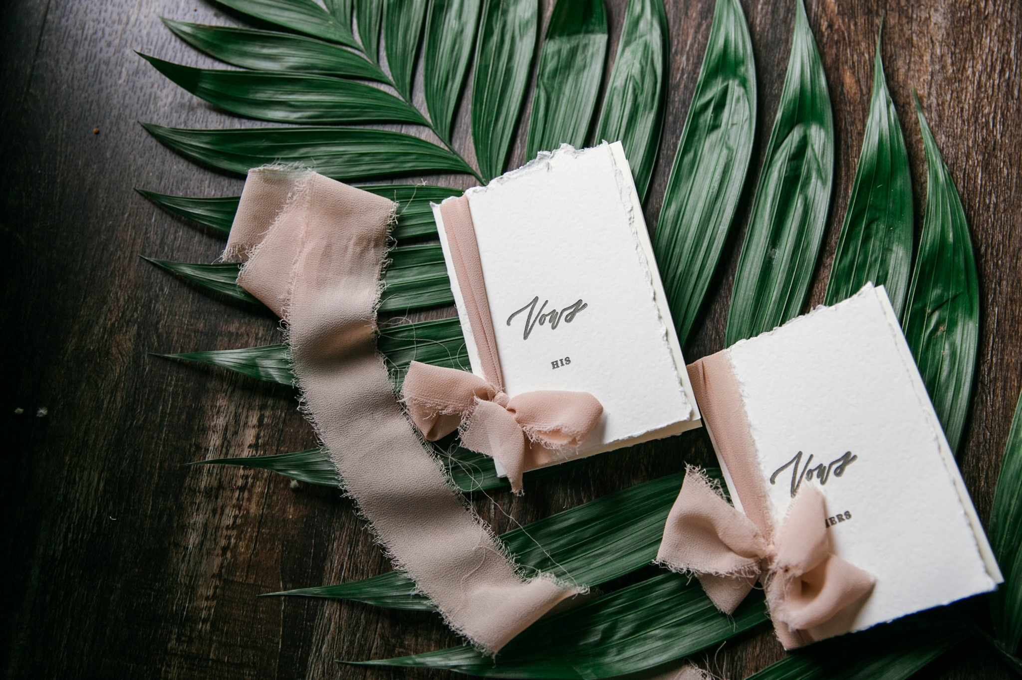  Lay flat of Wedding Vow books  with a tropical leave as the background with light pink ribbon styled by Johanna Dye Photography designed by Tortoise.Design - Tropical Destination Wedding Inspiration - Oahu Hawaii Wedding Photographer 