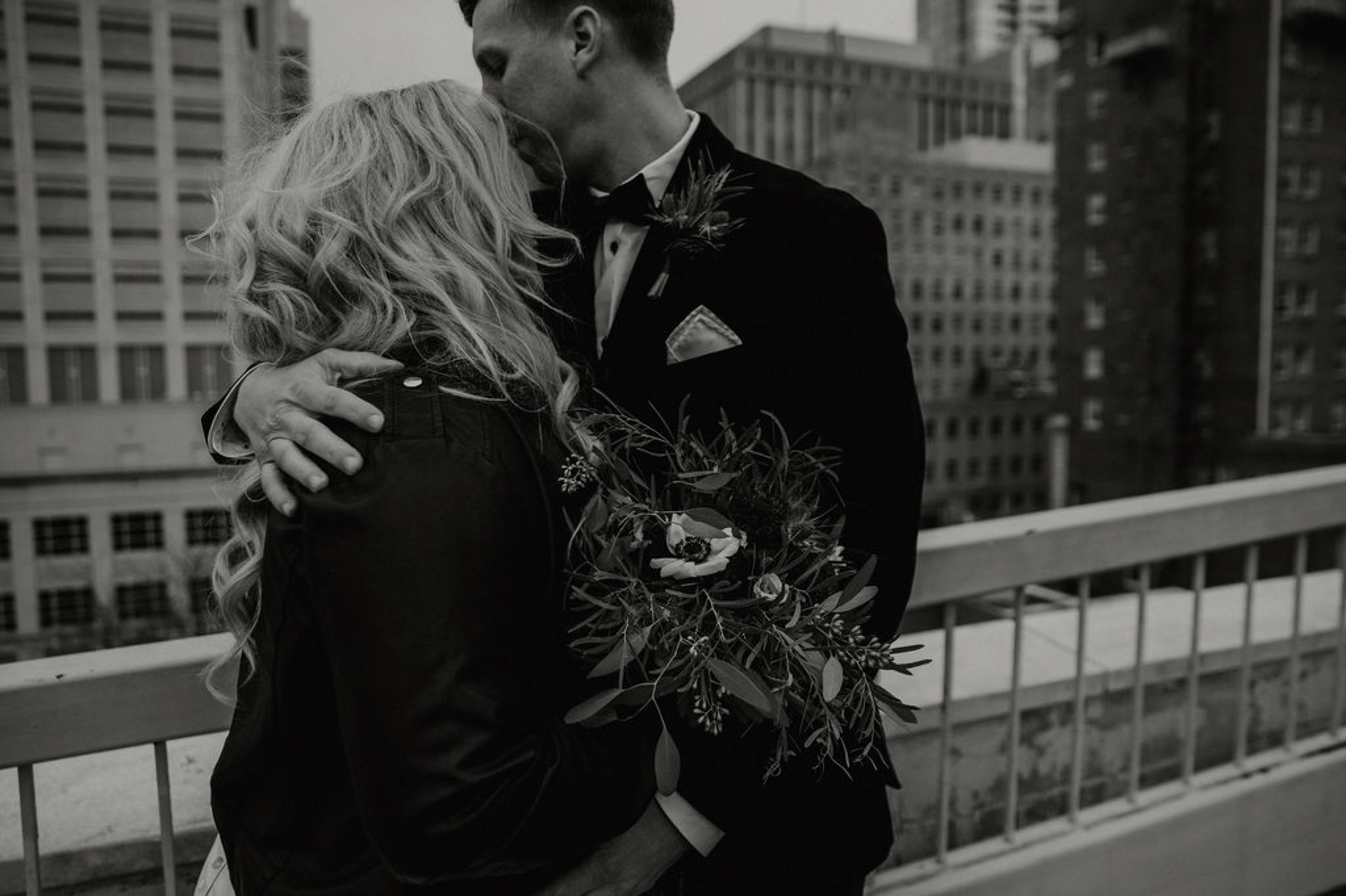 Wedding Portraits - Groom hugging bride - Bride in an Allure Bridals Mermaid Gown and a leather jacket - Burgundy Bridesmaids dresses by davids bridal Matt Smarsh and Johanna Dye - suites by the black tux - Raleigh North Carolina Urban Downtown Wedding - suits by the black tux