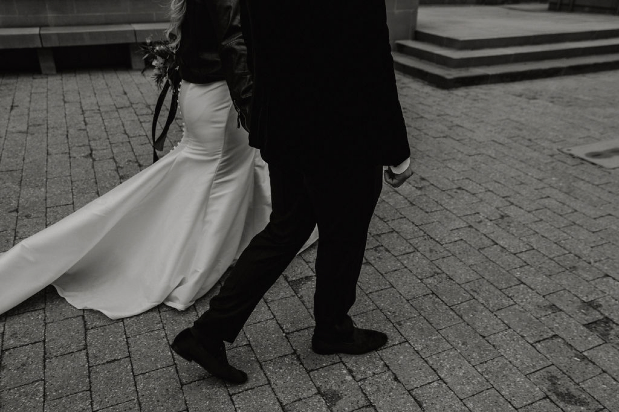 bride and groom walking downtown - Bride in an Allure Bridals Mermaid Gown and a leather jacket - Burgundy Bridesmaids dresses by davids bridal Matt Smarsh and Johanna Dye - suites by the black tux - Raleigh North Carolina Urban Downtown Wedding - suits by the black tux