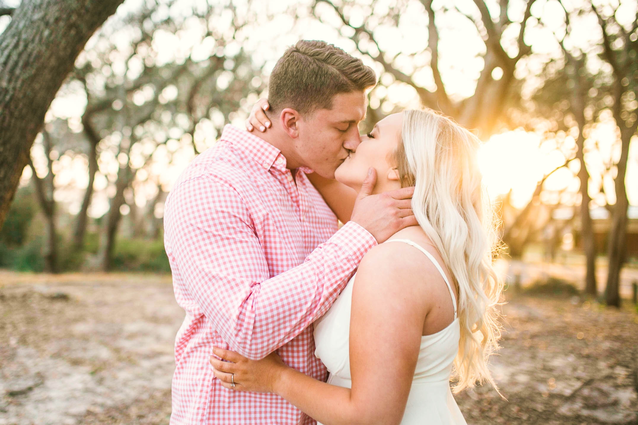  Engagement Photography Session beneath tropical trees at sunset during golden hour light -  man kissing his fiance - girl is wearing a white flowy maxi dress from lulus - Honolulu Oahu Hawaii Wedding Photographer - Johanna Dye 