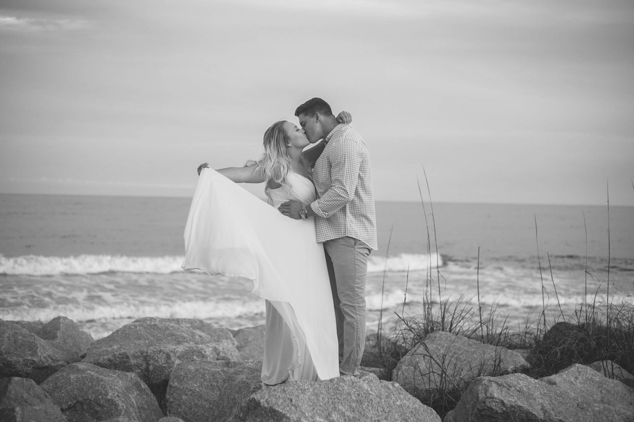  Black and White Engagement Photography Session at the beach on top of rocks  - couple is kissing - girl is wearing a white flowy maxi dress from lulus - Honolulu Oahu Hawaii Wedding Photographer - Johanna Dye 