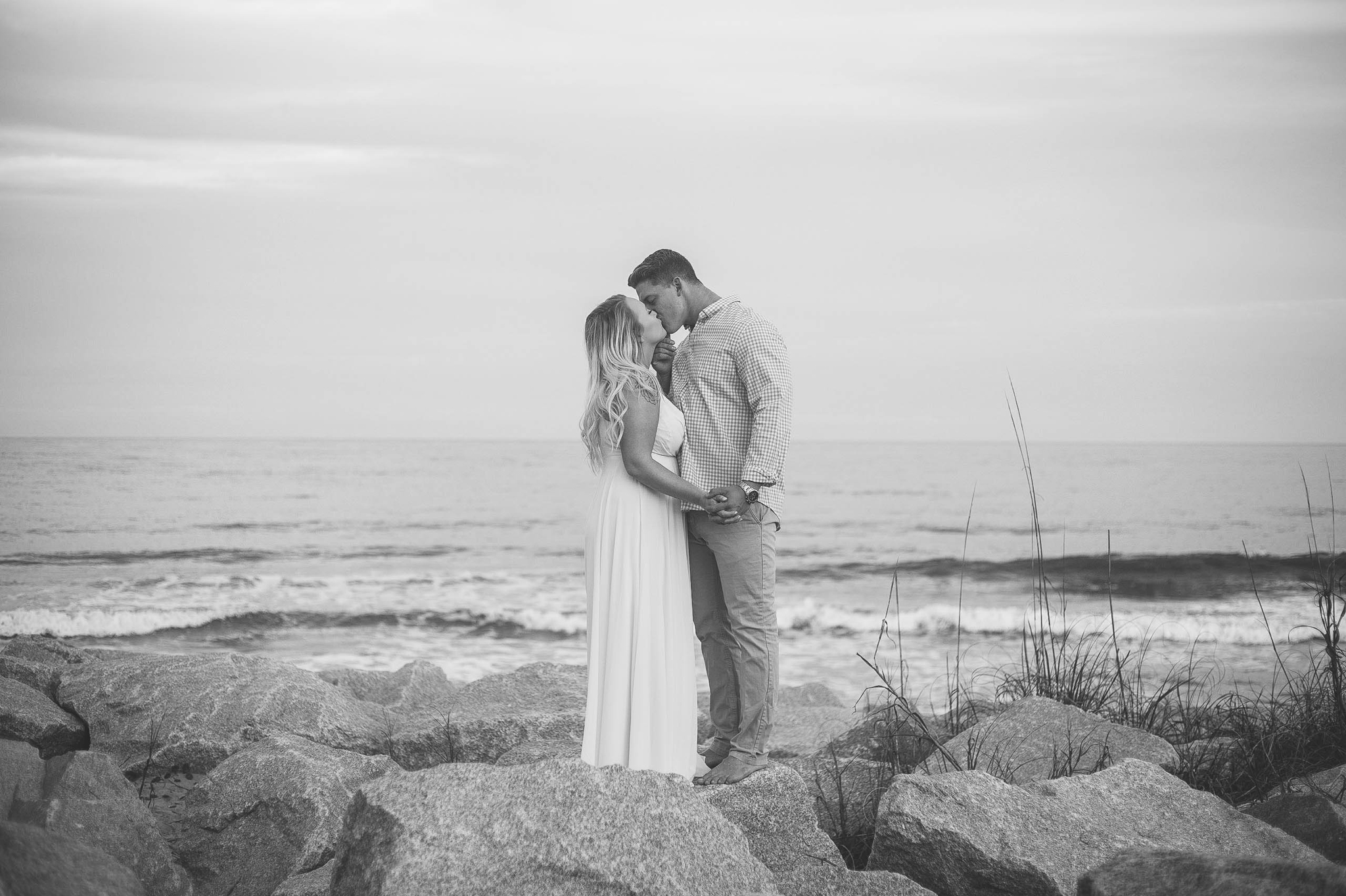  Black and White Engagement Photography Session at the beach on top of rocks - couple is kissing - girl is wearing a white flowy maxi dress from lulus - Honolulu Oahu Hawaii Wedding Photographer - Johanna Dye 