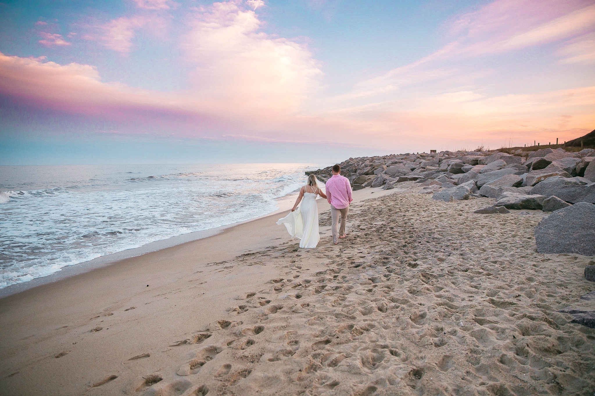  Romantic Engagement Photography Session at the beach during sunset with a cotton candy sky - couple is walking in the sand - girl is wearing a white flowy maxi dress from lulus - Honolulu Oahu Hawaii Wedding Photographer - Johanna Dye 