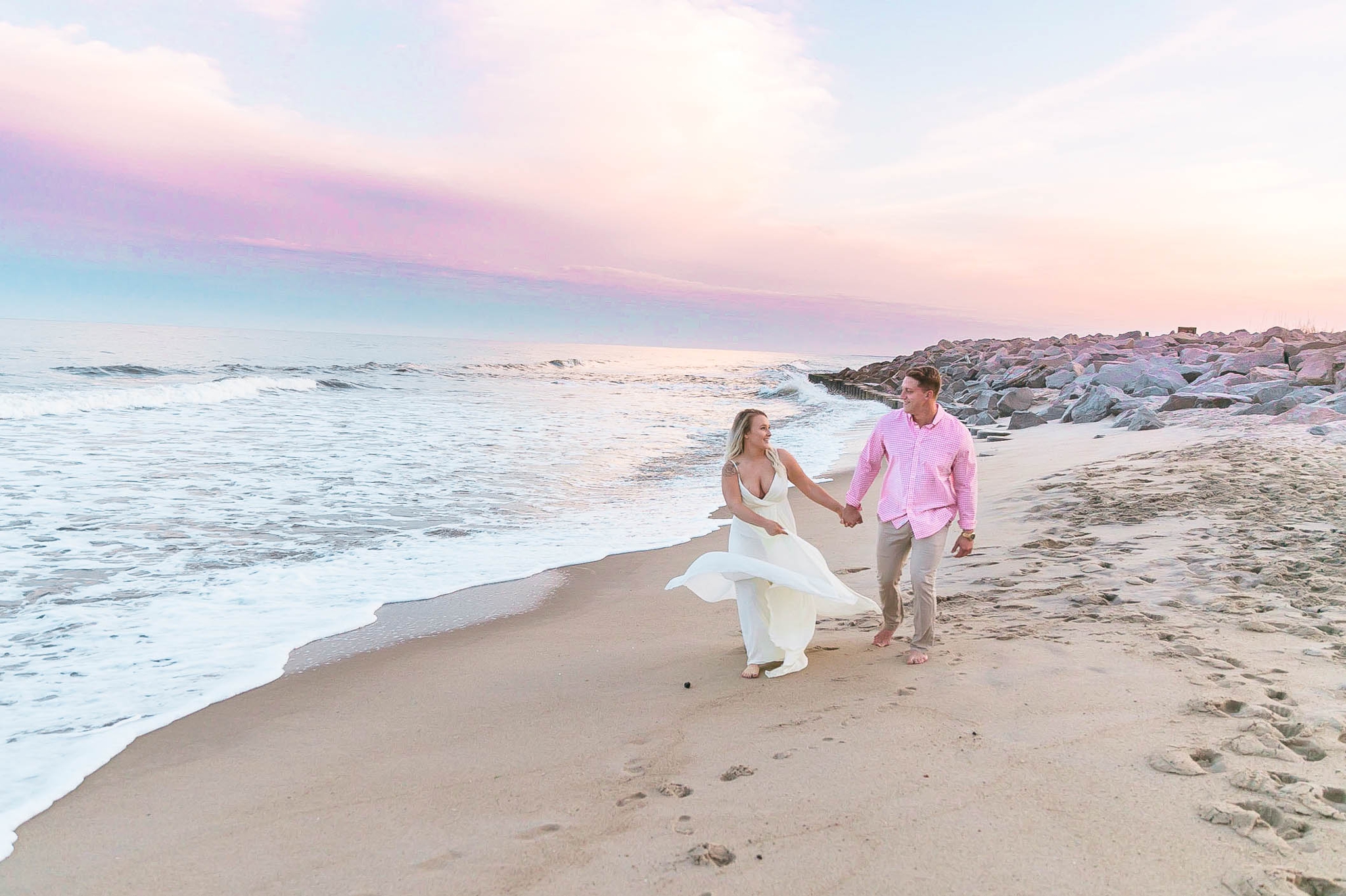  Romantic Engagement Photography Session at the beach during sunset with a cotton candy sky - couple is walking in the sand - girl is wearing a white flowy maxi dress from lulus - Honolulu Oahu Hawaii Wedding Photographer - Johanna Dye 