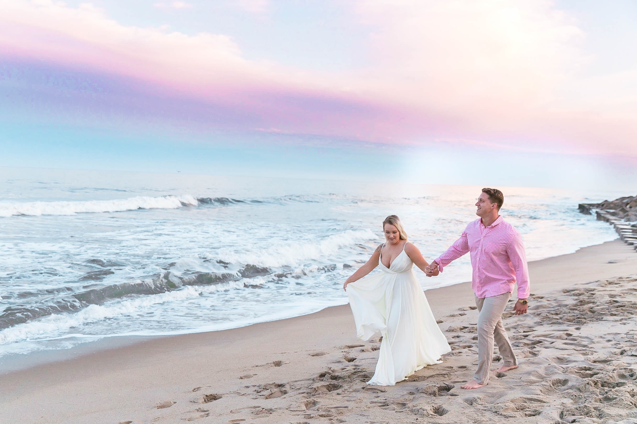  Romantic Engagement Photography Session at the beach during sunset with a cotton candy sky - couple is walking in the sand - girl is wearing a white flowy maxi dress from lulus - Honolulu Oahu Hawaii Wedding Photographer - Johanna Dye 