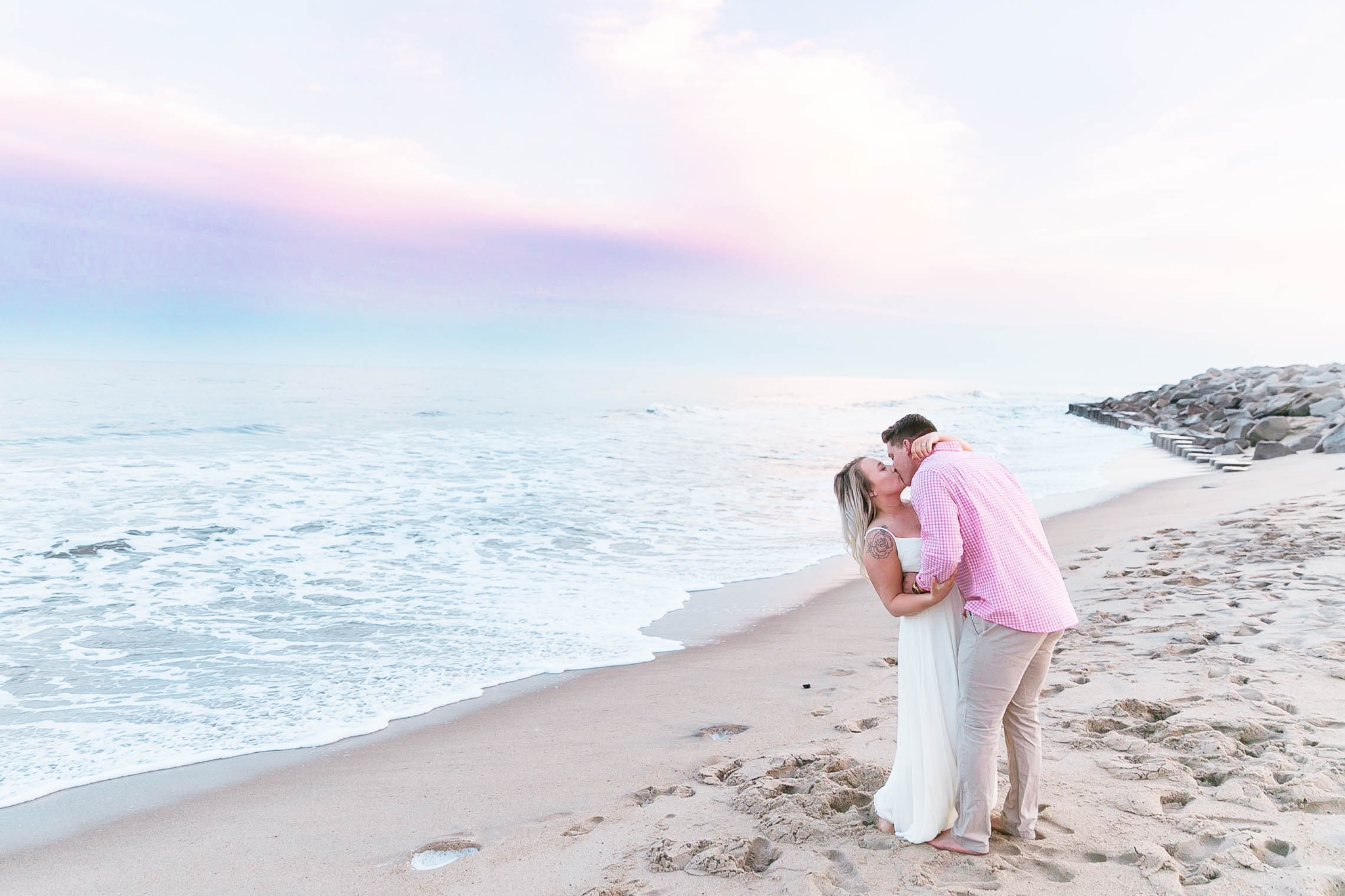  Romantic Engagement Photography Session at the beach during sunset with a cotton candy sky - guy is kissing his fiance - girl is wearing a white flowy maxi dress from lulus - Honolulu Oahu Hawaii Wedding Photographer - Johanna Dye 