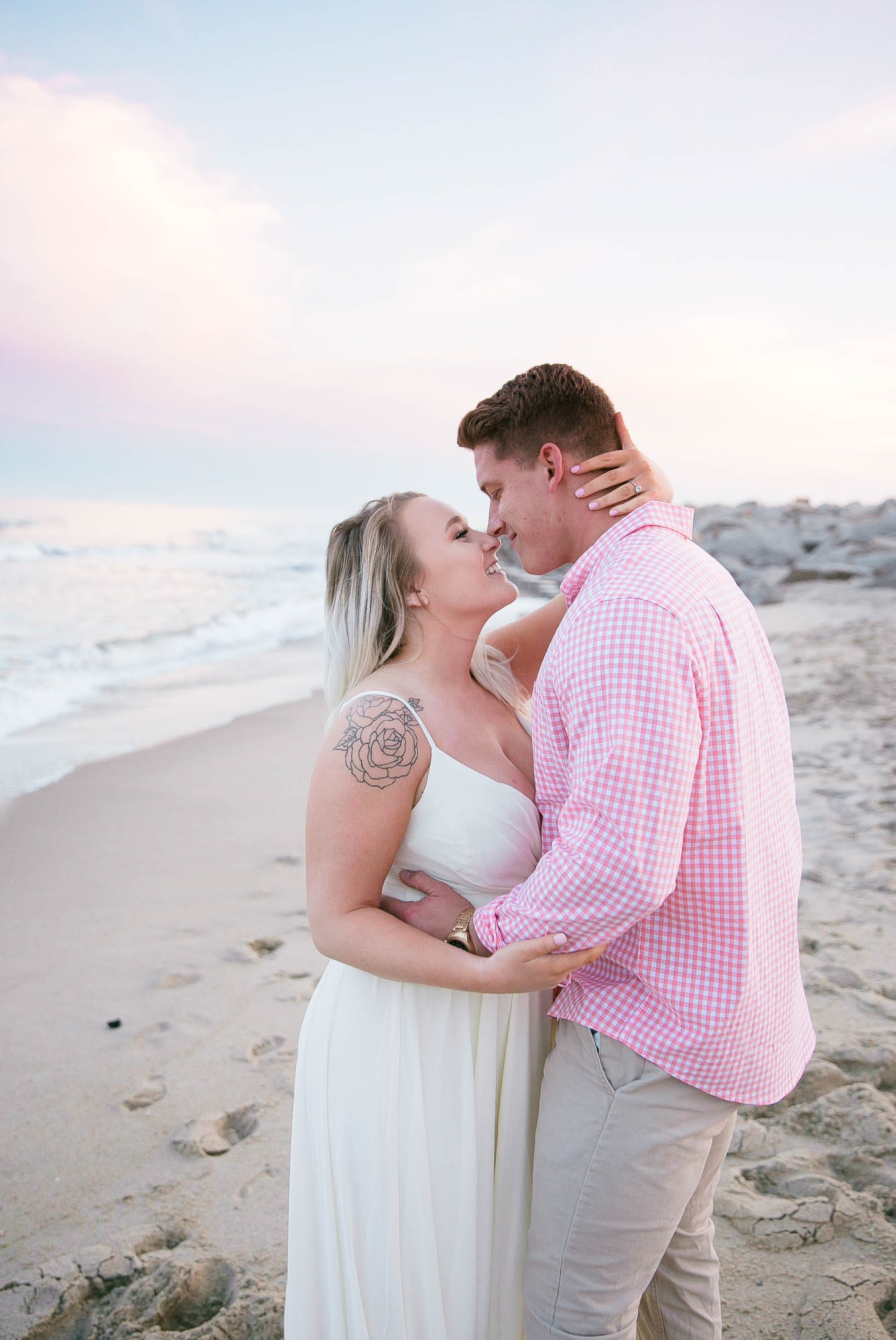  Romantic Engagement Photography Session at the beach during sunset with a cotton candy sky - guy is kissing his fiance - girl is wearing a white flowy maxi dress from lulus - Honolulu Oahu Hawaii Wedding Photographer - Johanna Dye 