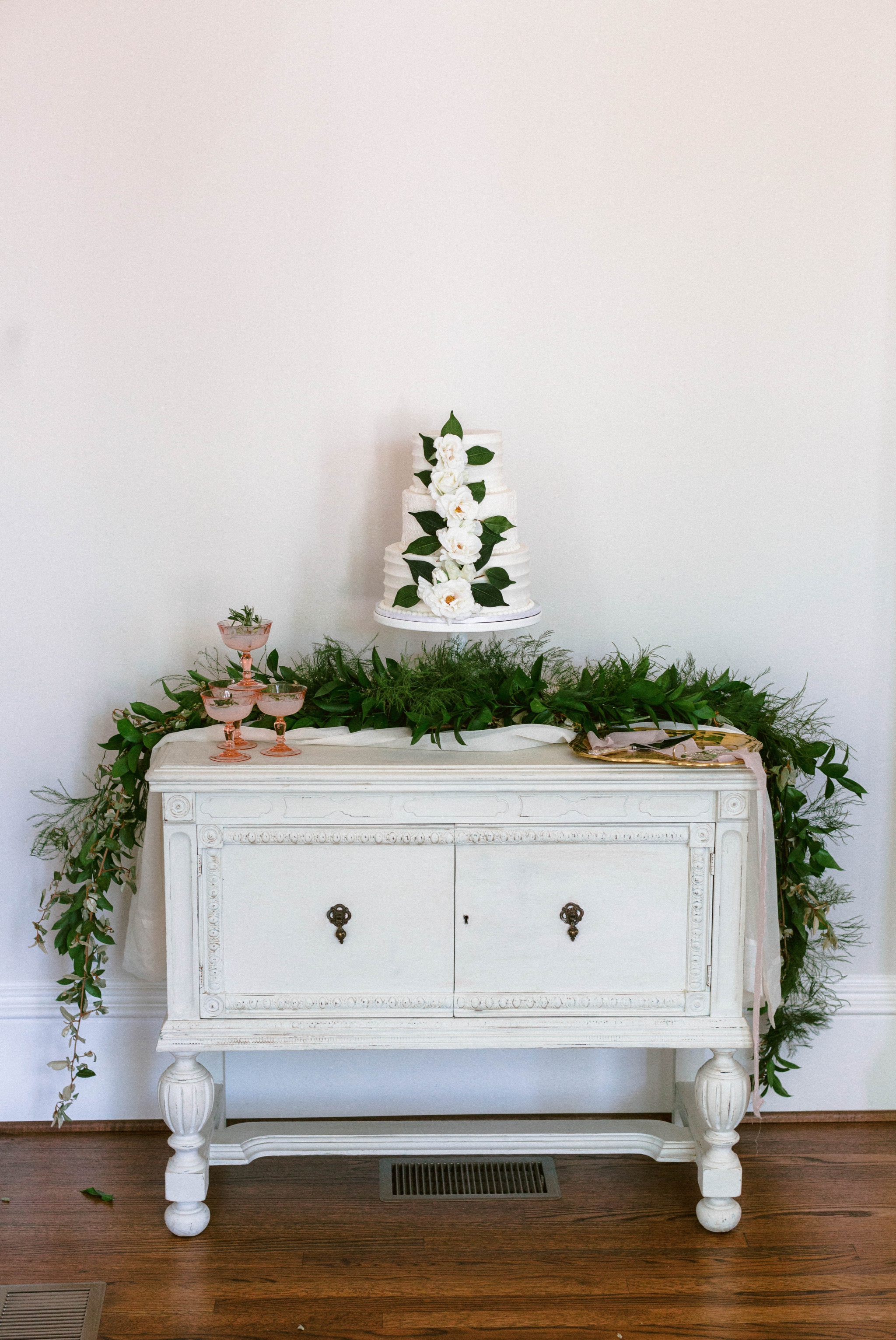  cake table on an all white antique dresser with an all white cake decorated with greenery -  luxury cake table inspiration - honolulu oahu hawaii wedding photographer - johanna dye photography 