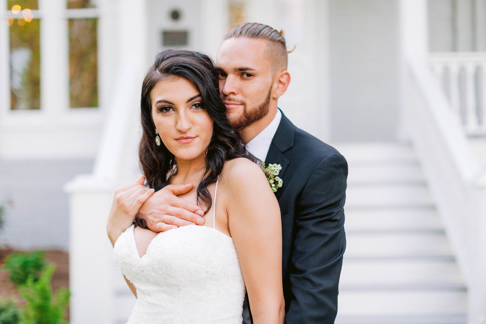   Wedding Portraits on the front porch of an all white luxury estate - Bride is wearing a Aline Ballgown by Cherish by Southern Bride with a long cathedral veil - Groom is wearing a black suit by Generation Tux and has a man bun - Fine Art Honolulu O