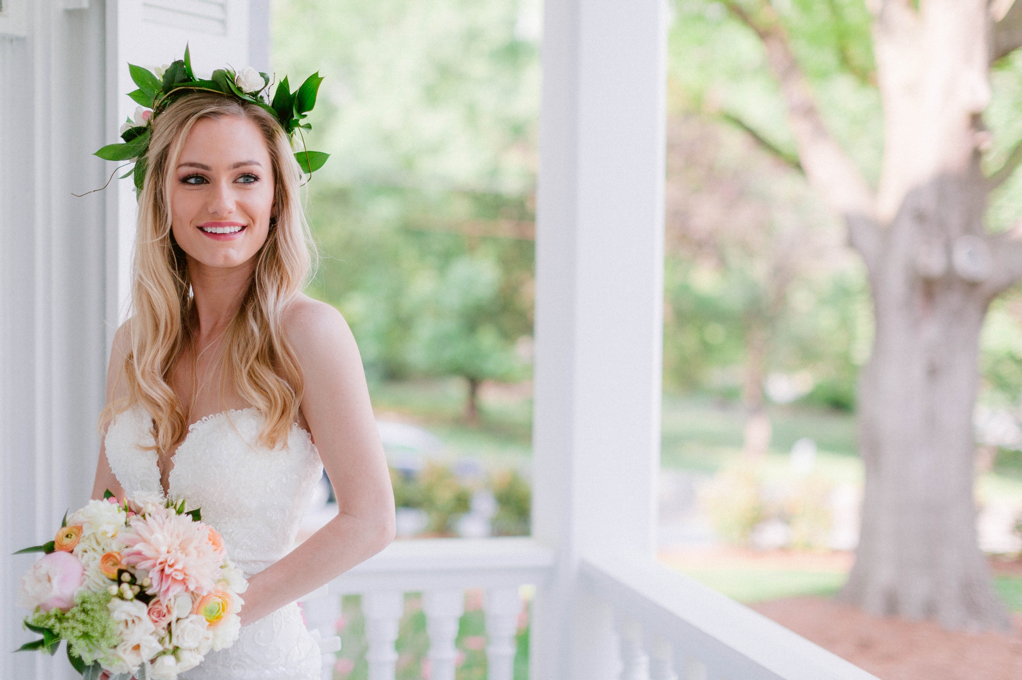  Indoor Bridal Portraits in an all white room at a luxury estate with natural light before the ceremony - Bride is wearing a Hawaiian Flower Crown in a Wedding Gown by Stella York and standing in the doorway with a golden chandelier with vintage furn