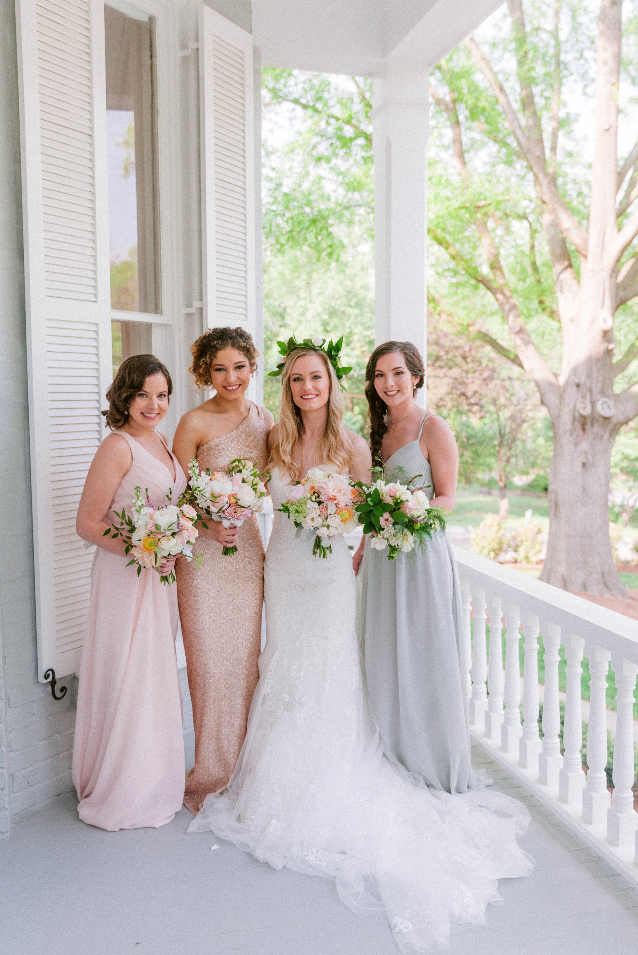   Bride + bridesmaids portraits in an all white room at a luxury estate with natural light before the ceremony sitting on a chair for an editorial shot - Bride is wearing a Hawaiian Flower Crown and a cathedral veil in a Wedding Gown by Stella York -