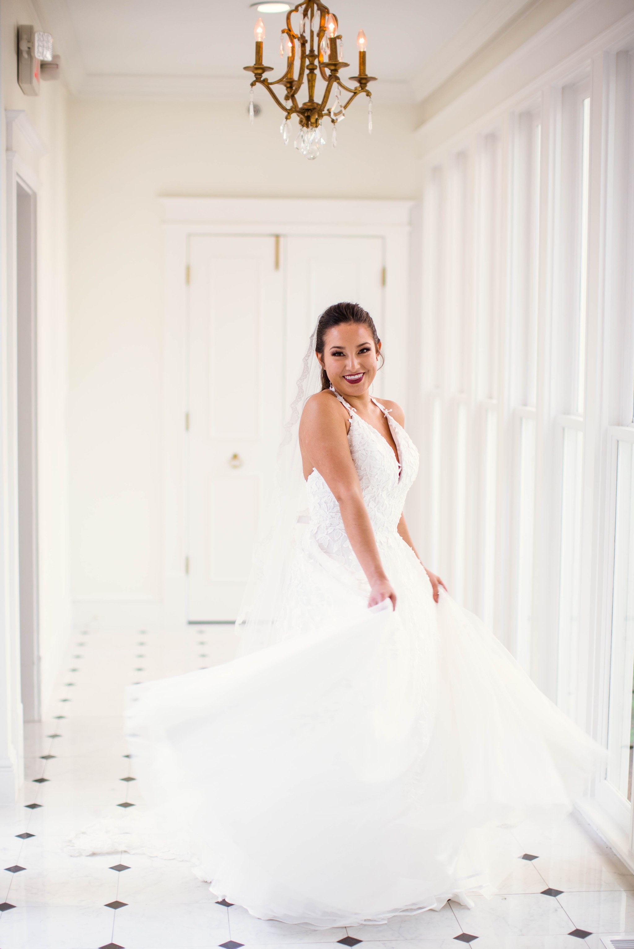  Natural light Bridal Portraits in an all white luxury estate venue with black and white floors and a golden chandelier - Bride is wearing a Ballgown Wedding Dress by Sherri Hill - shot with available window light - Fine Art Wedding Photographer in H