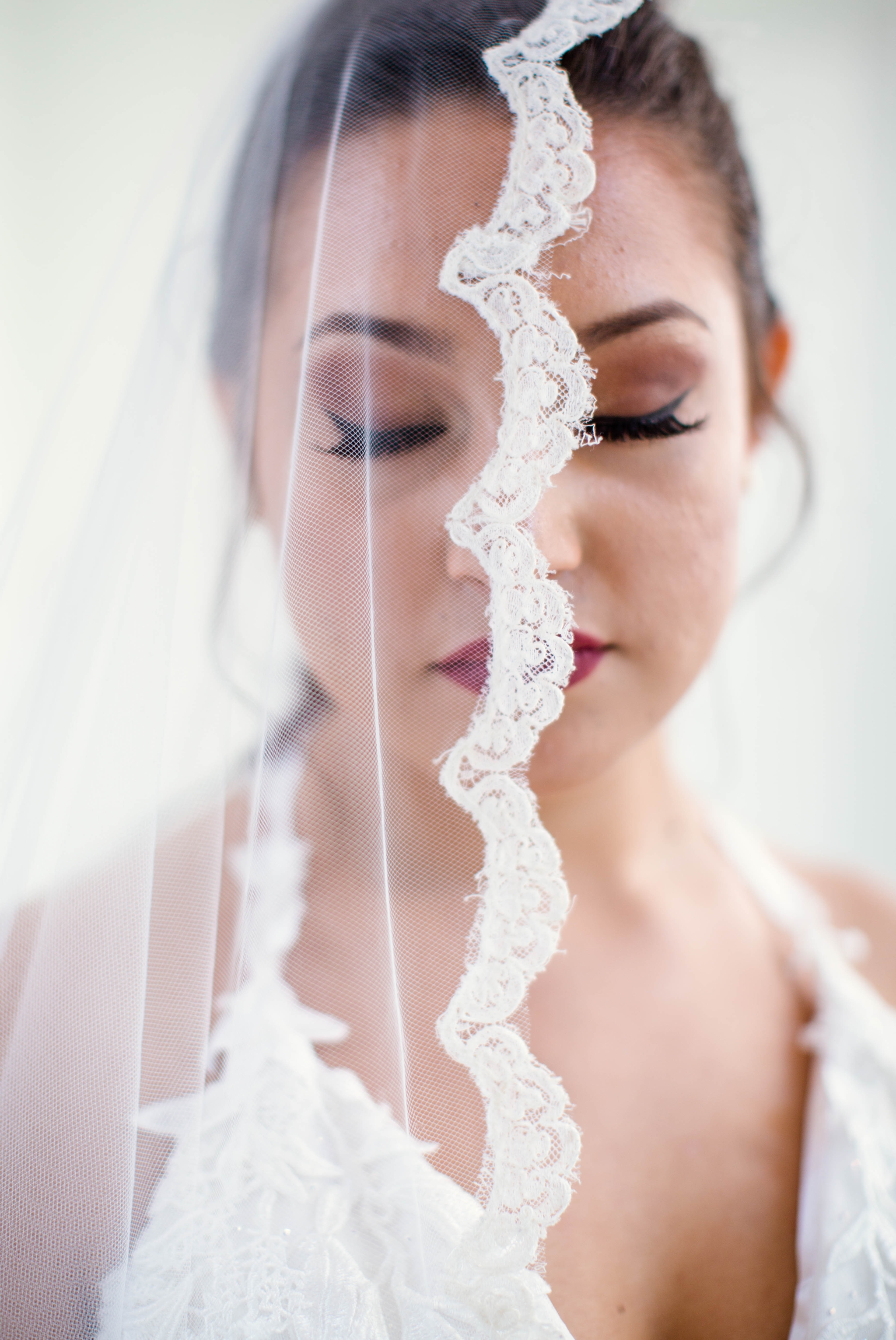  Bridal Beauty Shot with the veil over her face - Natural light Bridal Portraits in an all white luxury estate venue with black and white floors and a golden chandelier - Bride is wearing a Ballgown Wedding Dress by Sherri Hill - shot with available 