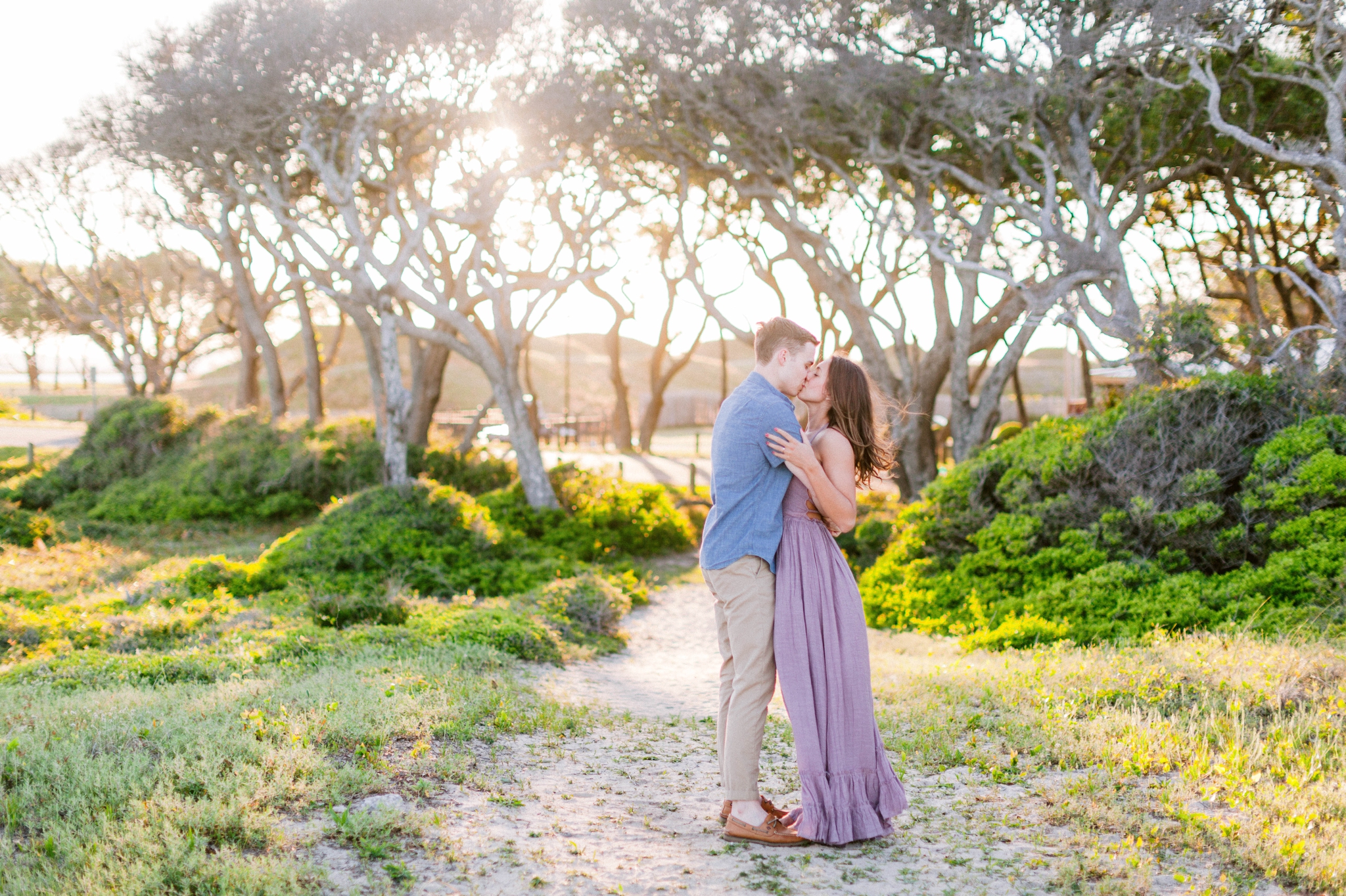  Guy dancing with girl in front of live oak trees with the sunset behind them - Woman is in a flowy pastel maxi dress - unposed and candid outdoor golden light session - engagement photographer in honolulu, oahu, hawaii - johanna dye photography 