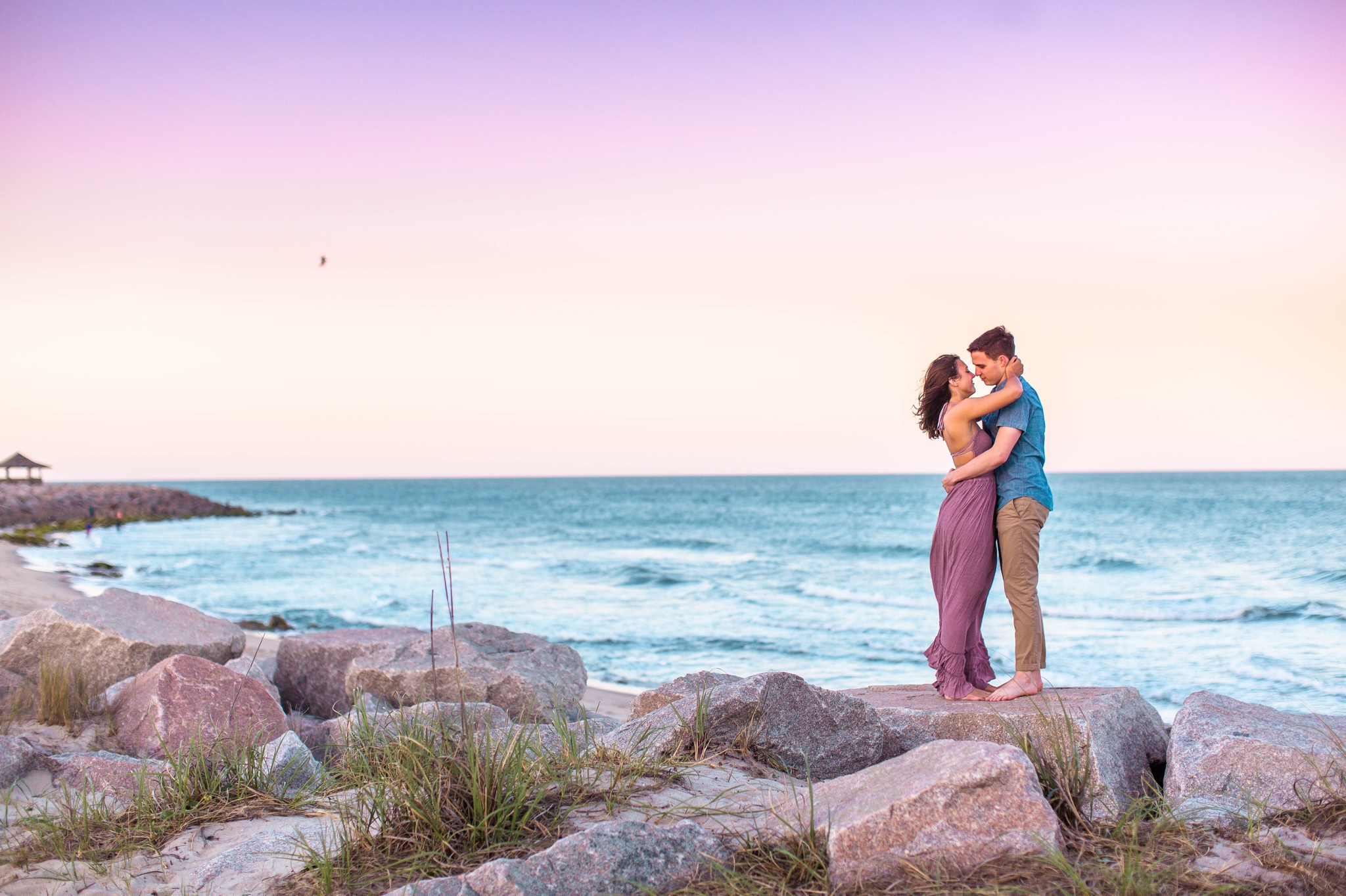 Couple kissing on the cliffs at sunset - Woman is in a flowy pastel maxi dress - candid and unposed golden light session - beach engagement photographer in honolulu, oahu, hawaii - johanna dye photography 