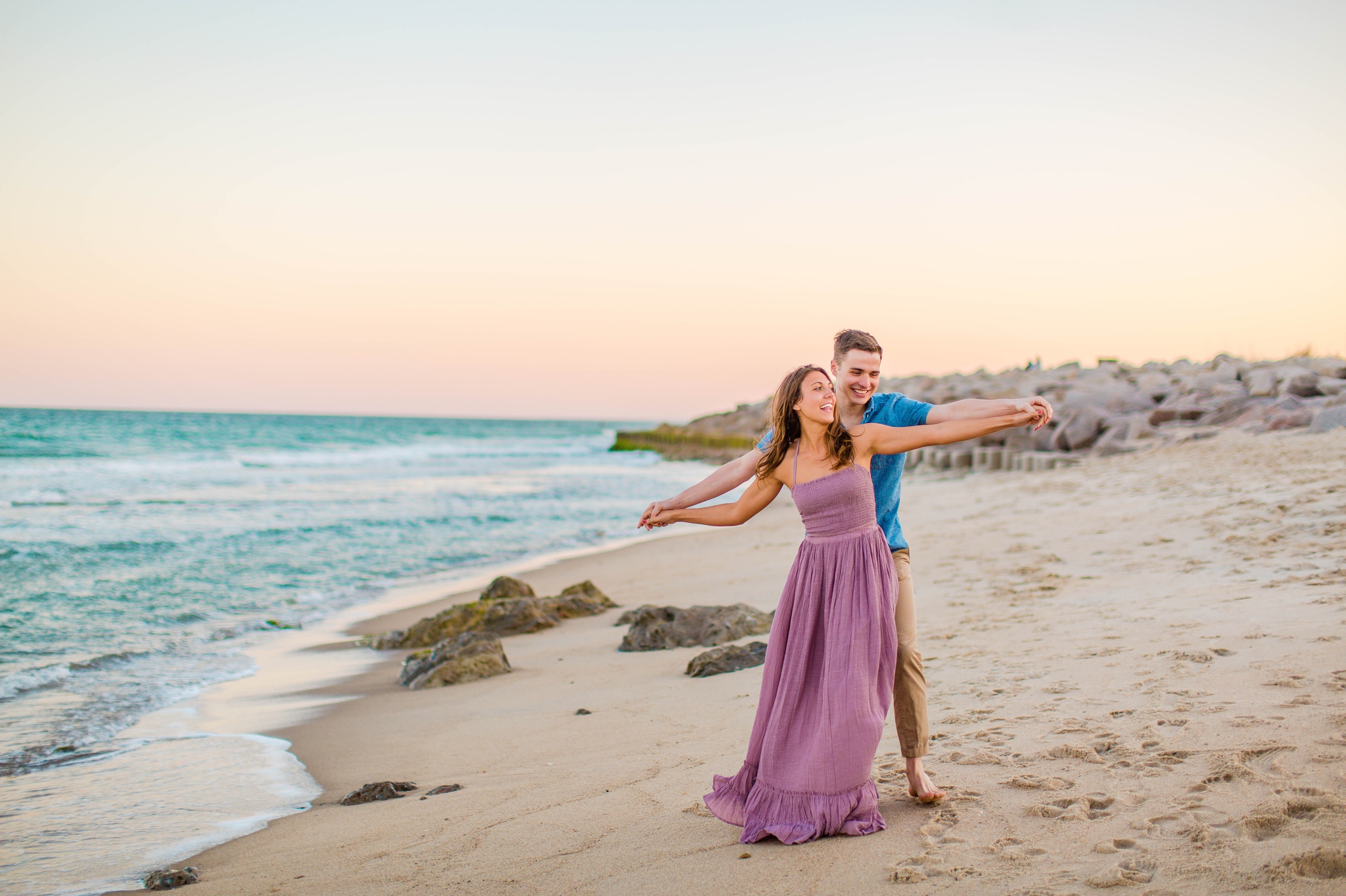  couple playing around on the beach - - Woman is in a flowy pastel maxi dress - candid and unposed golden light session - beach engagement photographer in honolulu, oahu, hawaii - johanna dye photography 