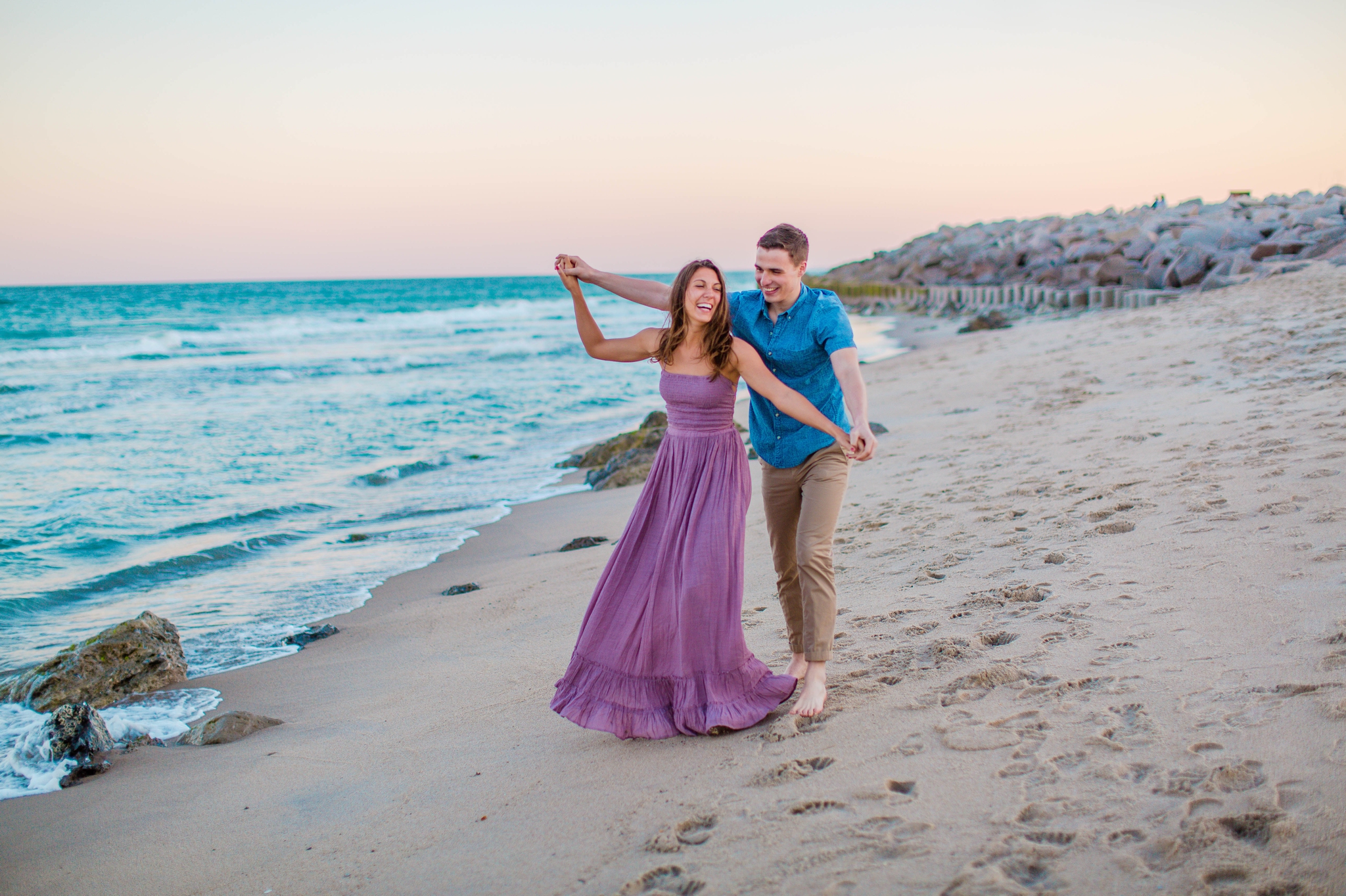  couple playing on the beach - Woman is in a flowy pastel maxi dress - candid and unposed golden light session - beach engagement photographer in honolulu, oahu, hawaii - johanna dye photography 