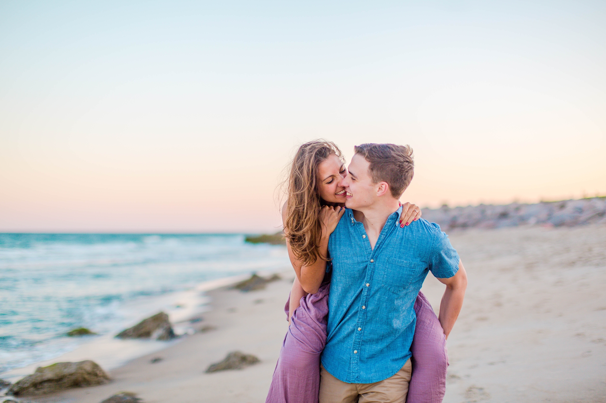  piggyback riding at the beach - - Woman is in a flowy pastel maxi dress - candid and unposed golden light session - beach engagement photographer in honolulu, oahu, hawaii - johanna dye photography 