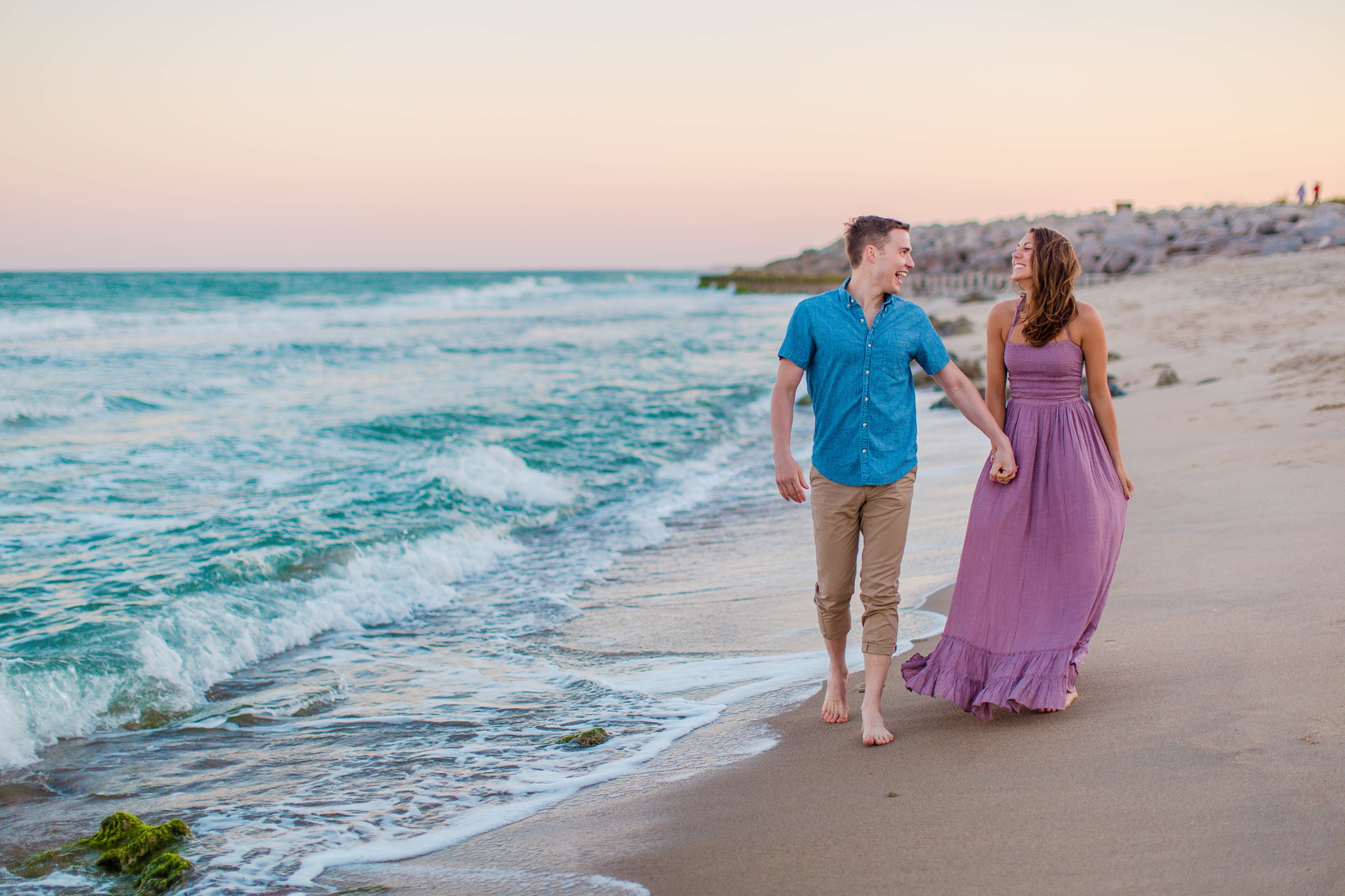  GUY AND his fiance walking in the water - - Woman is in a flowy pastel maxi dress - candid and unposed golden light session - beach engagement photographer in honolulu, oahu, hawaii - johanna dye photography 