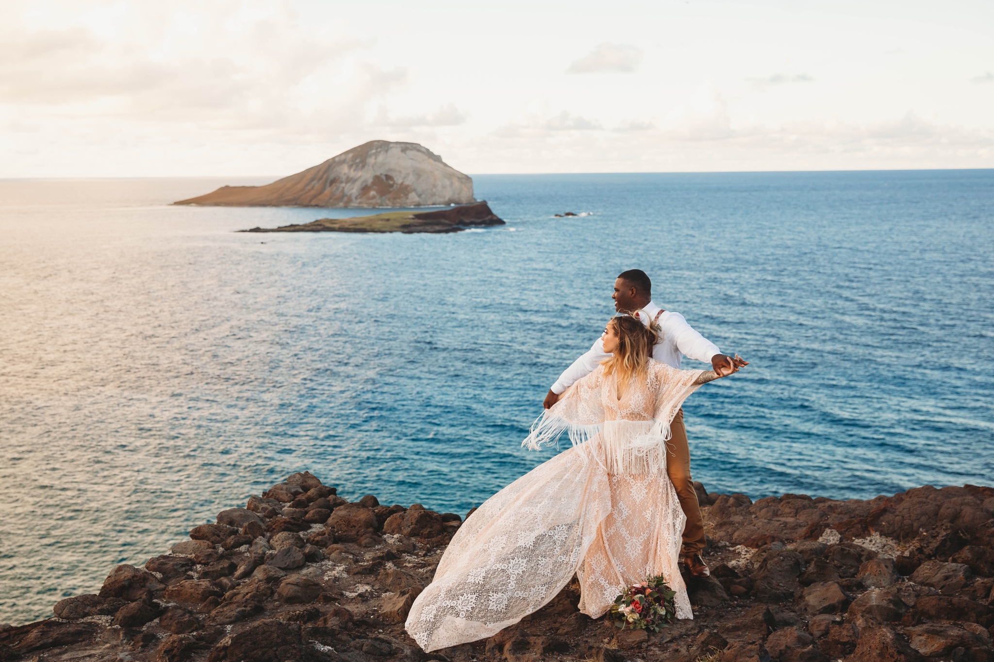 couple on the cliffs above Makapuu Beach at the Lookout, Waimanalo, HI - Oahu Hawaii Engagement Photographer - Bride in a flowy fringe boho wedding dress - lanikai lookout - deutsche hochzeits fotografin in hawaii - smal1 - dark and moody - true to live