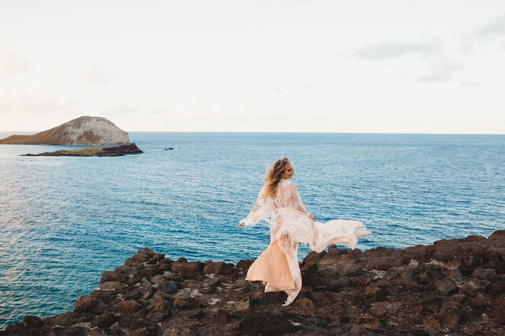  Bride in a flowy fringe boho wedding dress on the cliffs above Makapuu Beach at the Lookout, Waimanalo, HI looking over the ocean with the  Kāohikaipu Island in the background  - Oahu Hawaii Engagement Photographer - lanikai lookout - deutsche hochz