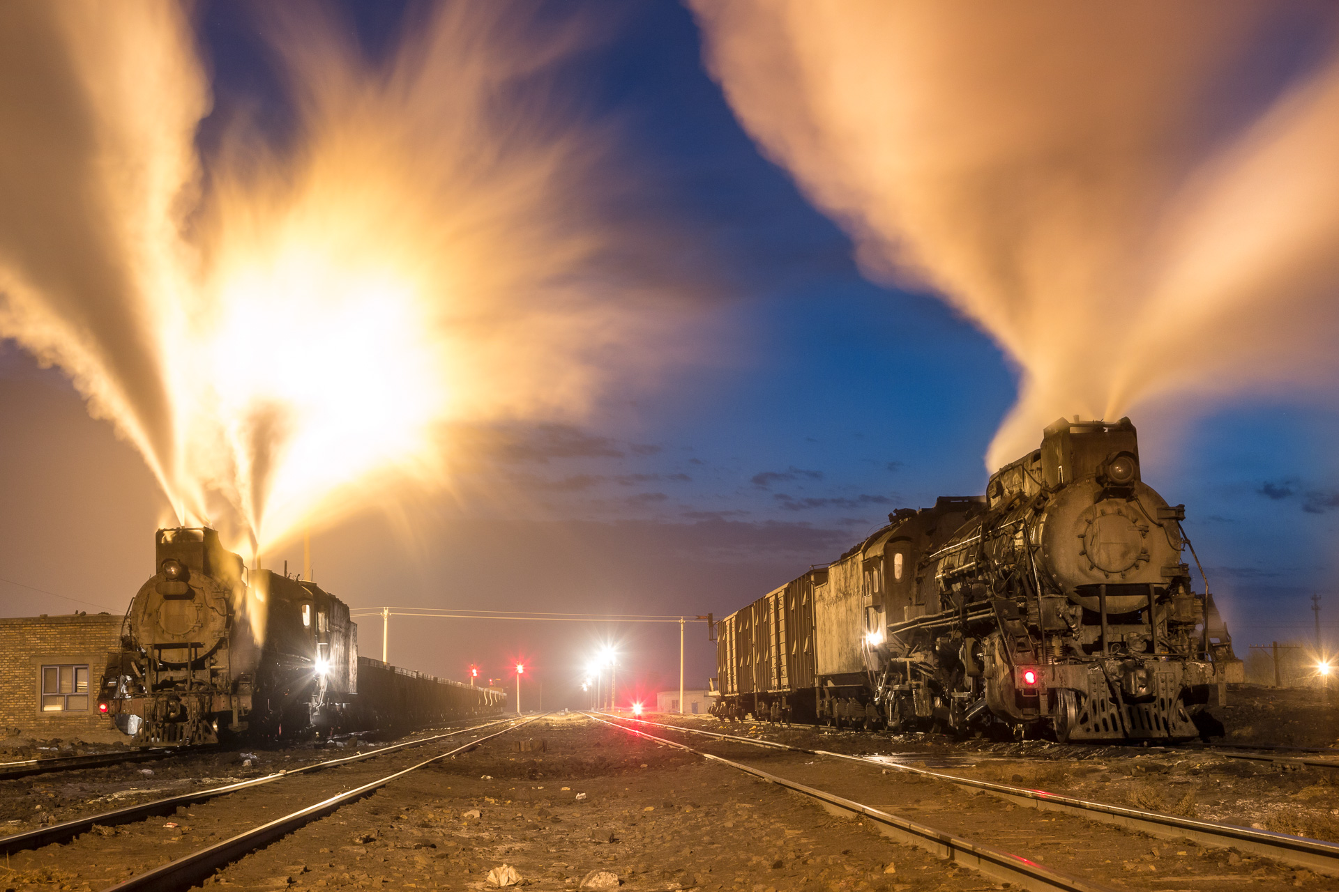  Vor Sonnenaufgang treffen sich zwei Lokomotiven der  JS  Klasse in Dongbolizhan, Provinz Xinjiang. Die Dezemberkälte von minus 20 Grad lässt die Dampfwolken weit in den Himmel steigen. 